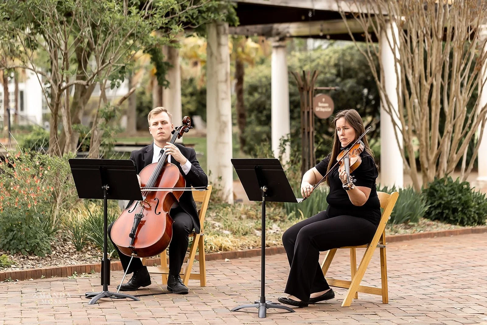 two musicians play string instruments for an outdoor wedding in belmont nc at stowe conservancy botanical garden