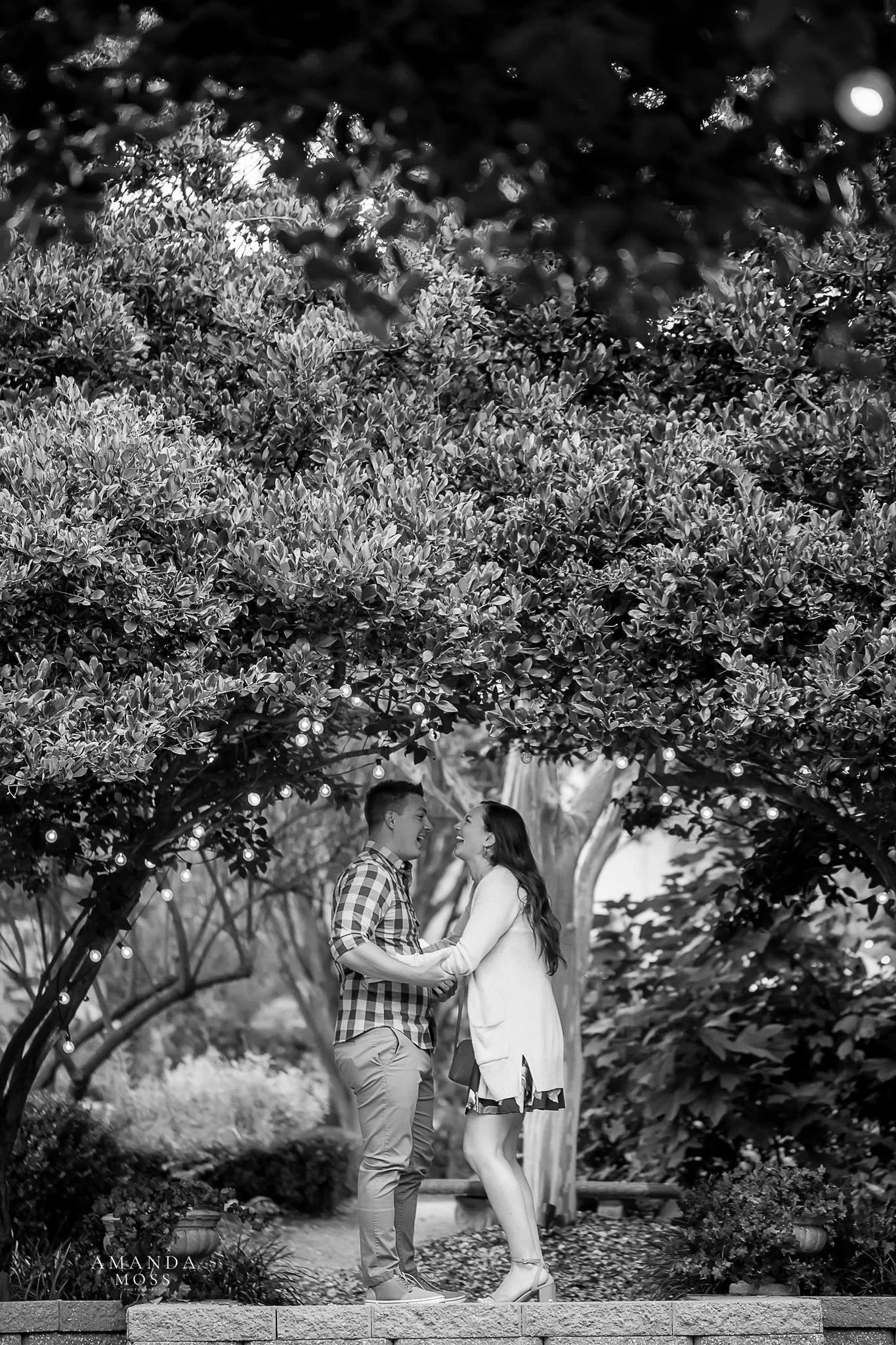 black and white photo of couple jumping for joy after marriage proposal