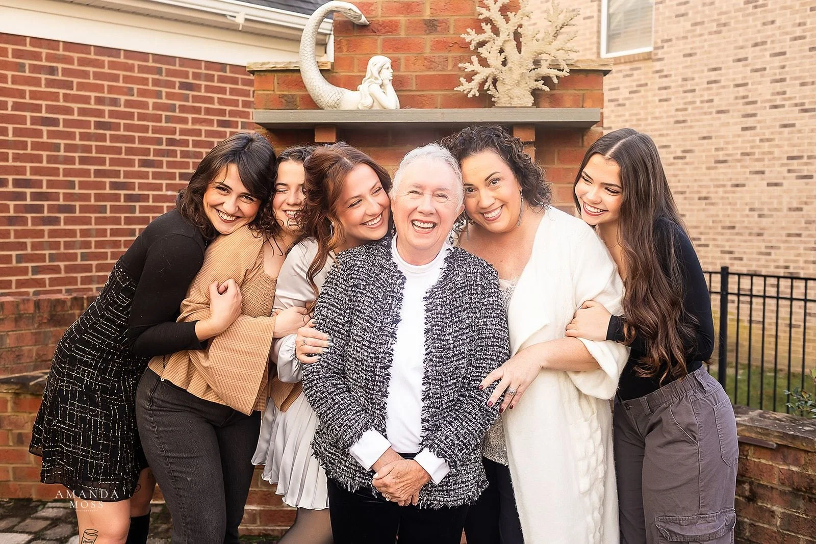 grandmother and her daughter and adult grandchildren hug in matriarchal family photo at charlotte home