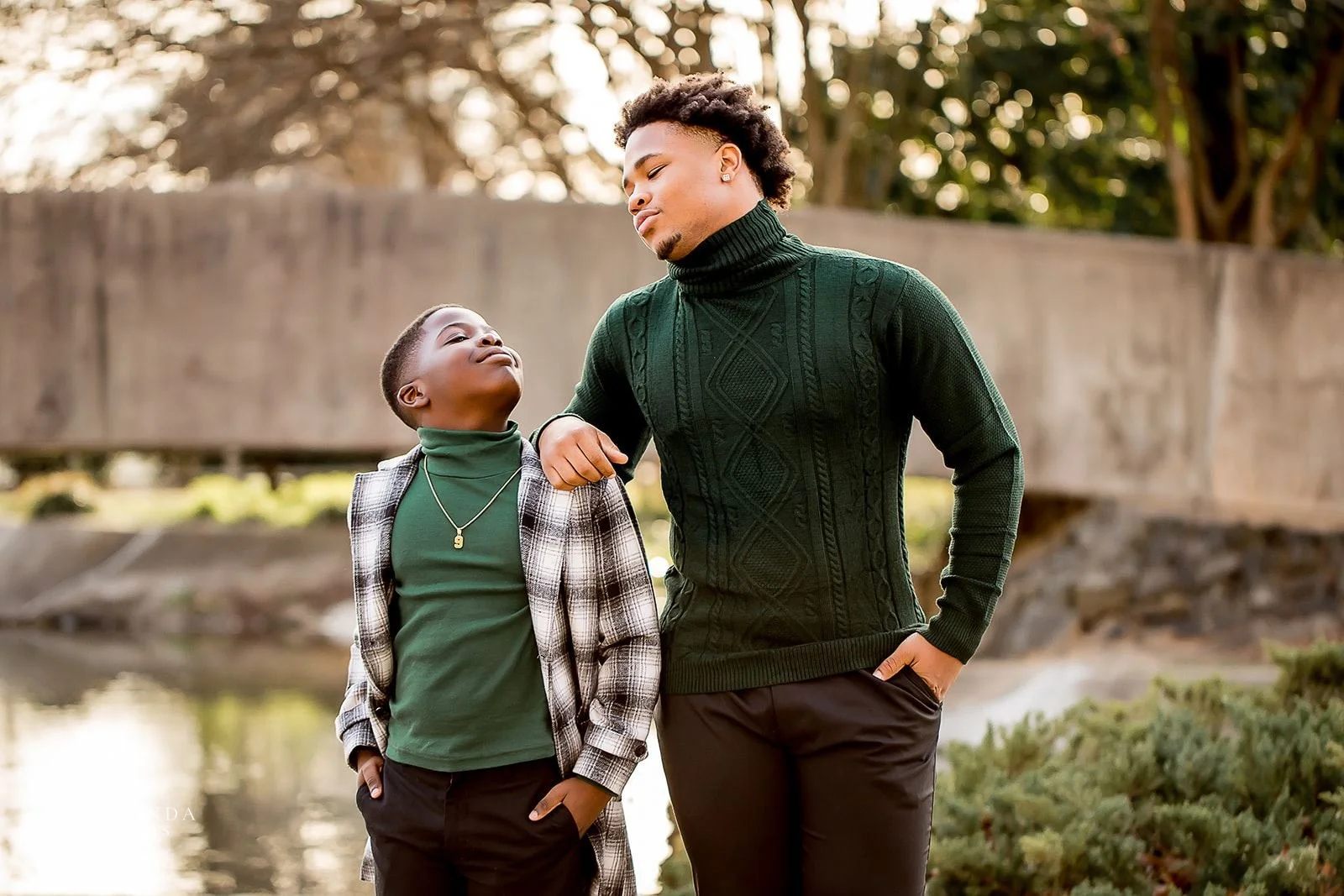 two sons wearing emerald green pose and look at each other during outdoor family session at marshall park in charlotte nc
