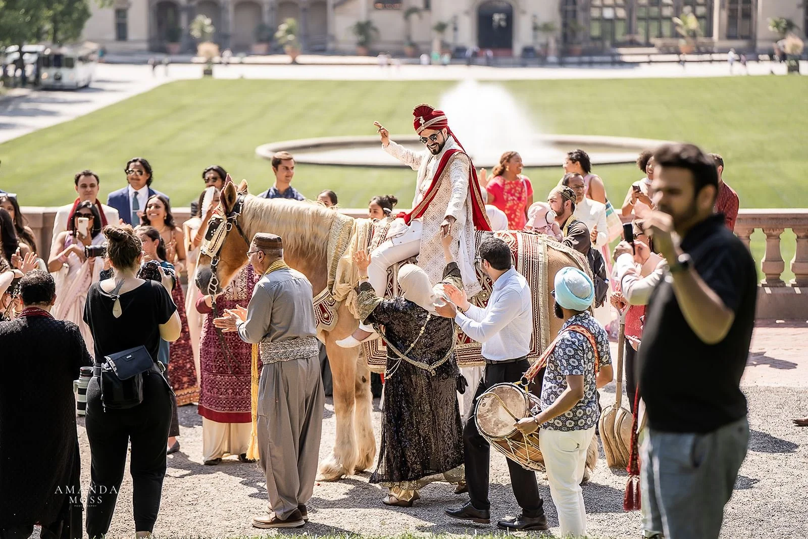 Groom celebrates on horse while surrounding by friends and family during baraat at hindu wedding biltmore estate asheville nc