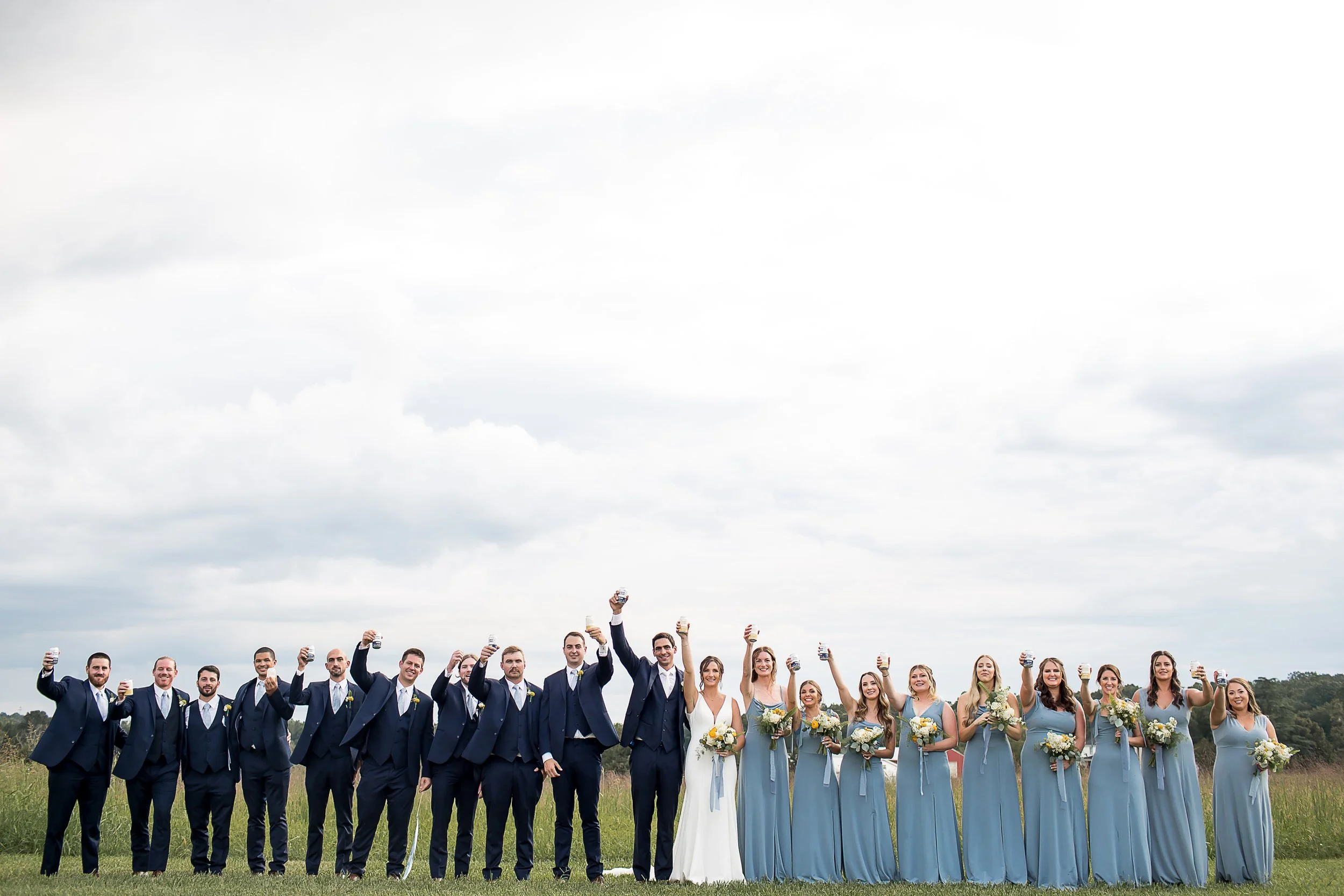 large wedding party 20 people bridal cheers for a photo