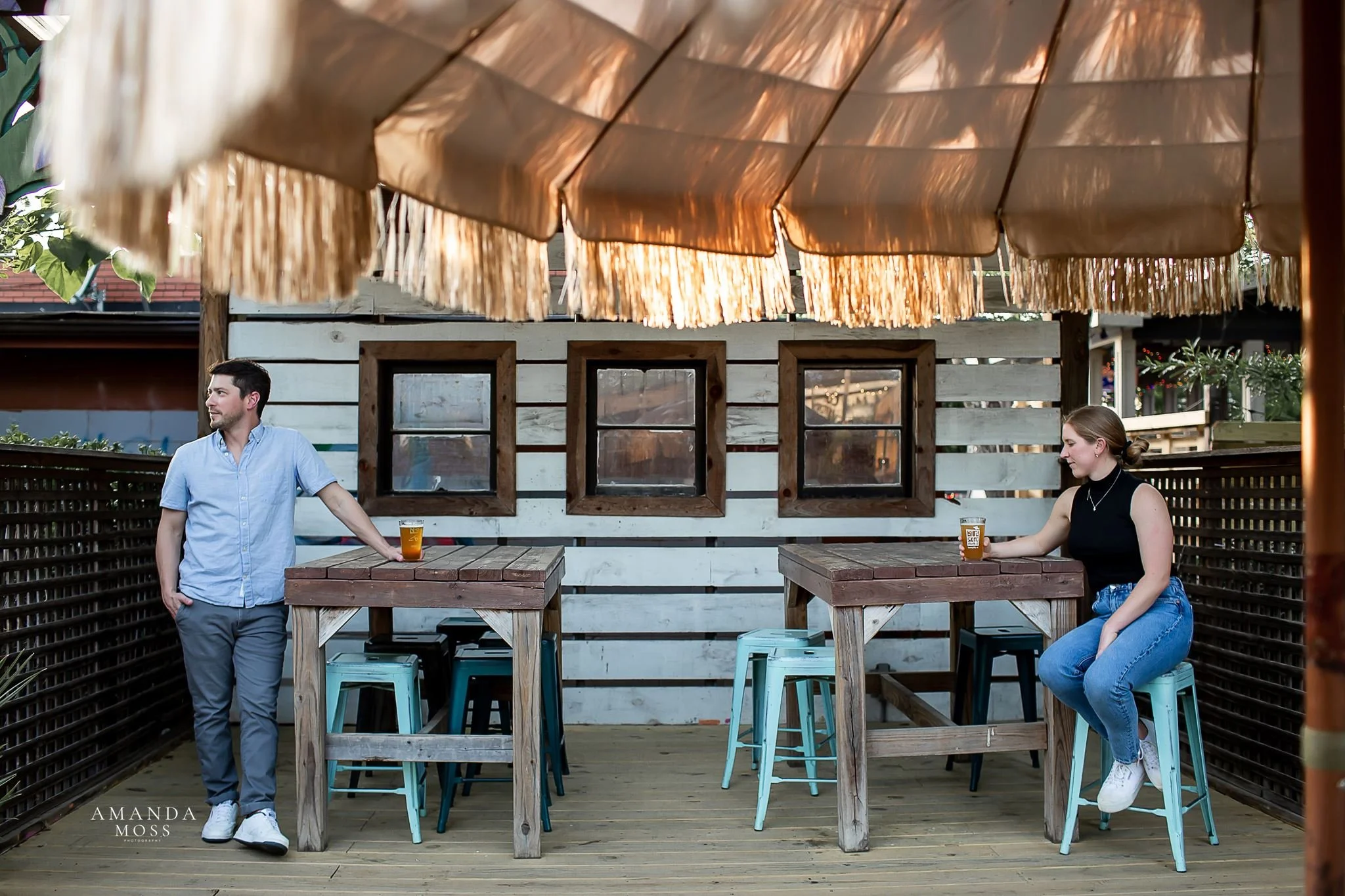 couple casually hangs out at outdoor bar patio for engagement session date night in noda charlotte nc