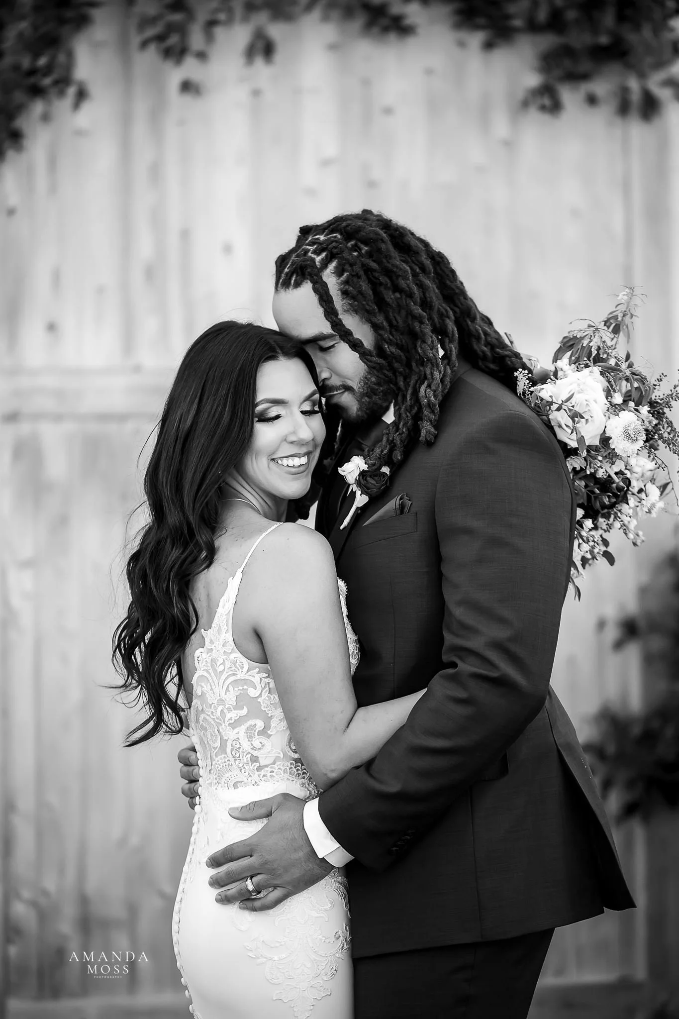 black and white portrait of interracial bride and groom embracing after wedding ceremony