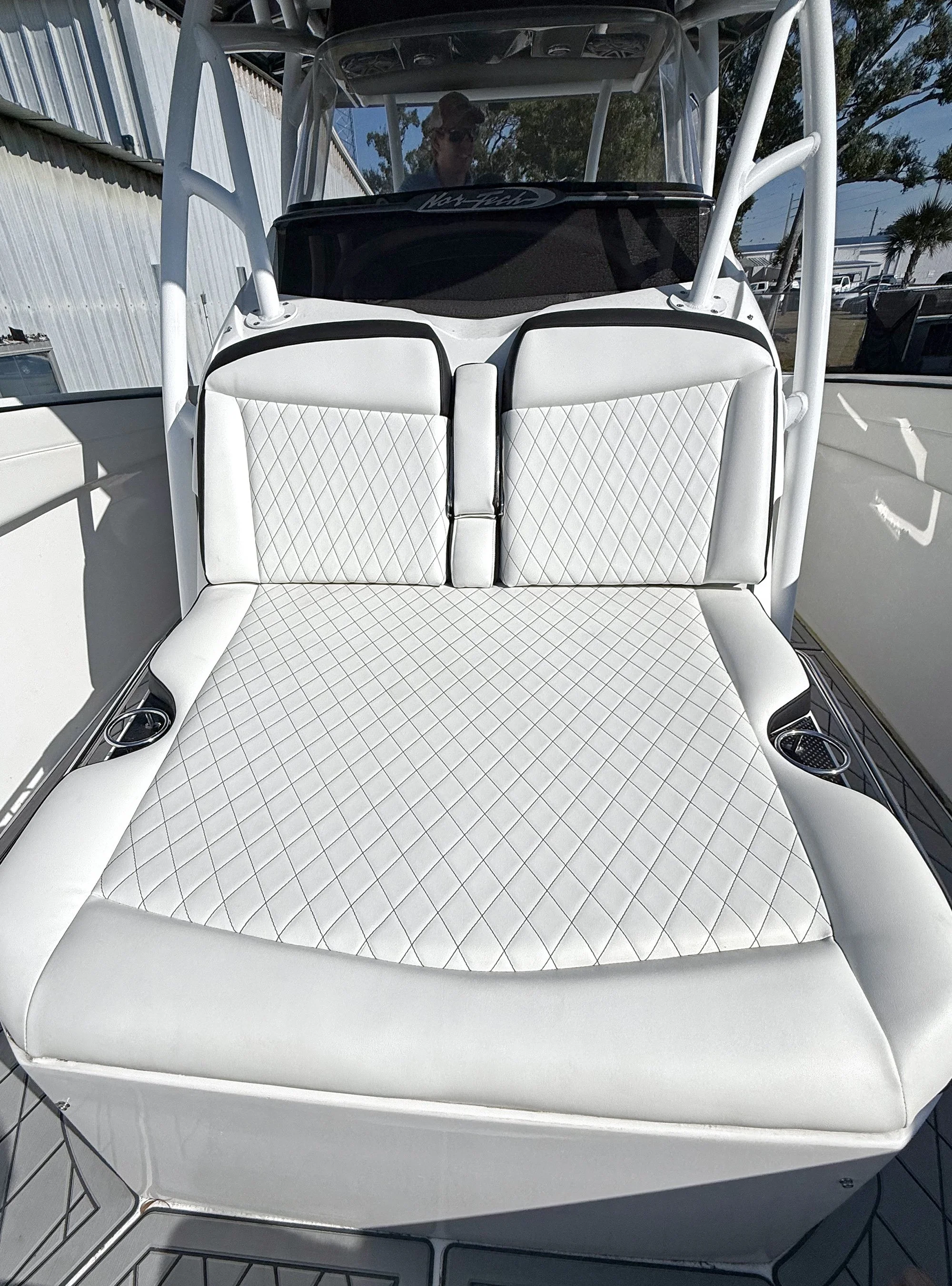 Front view of a boat with a white cushioned seating area and a clear plastic windshield.