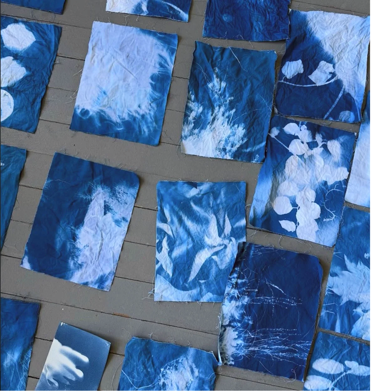 A collection of crumpled and flat blue tie-dye fabric pieces arranged on a tan surface.
