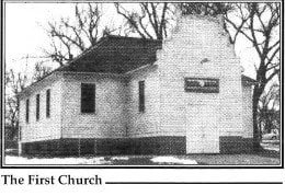 Black and white photo of a small historic house labeled 'The First Church' with a chimney, below a leafless tree-lined sky.