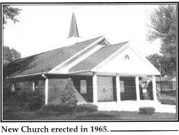 Black and white photo of a new church built in 1965 with a steeple, surrounded by trees.