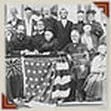 Historical black and white photograph of a group of men in formal attire, with an American flag draped in front, suggesting a patriotic or official event.