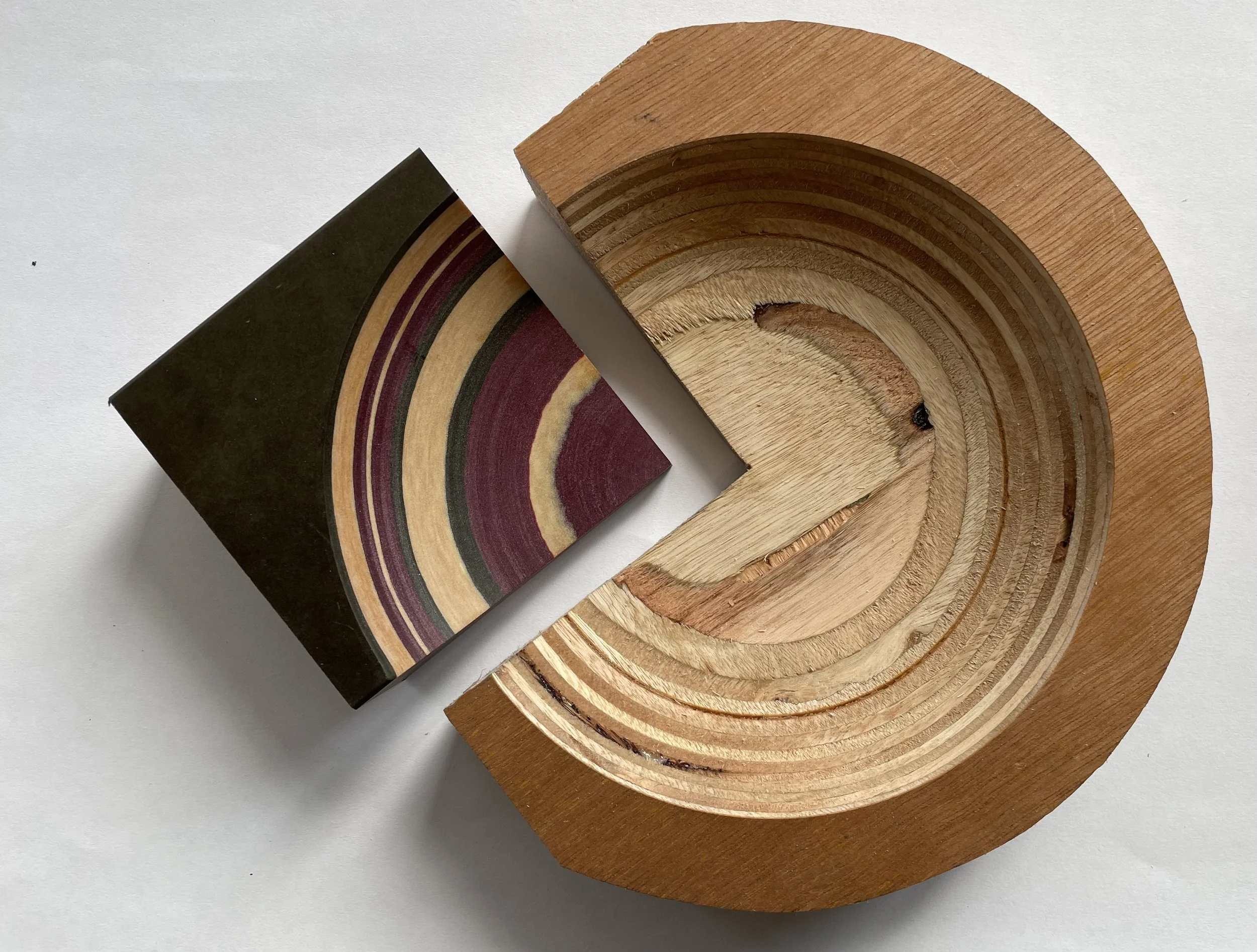 Close-up of layered wooden circles, with a box showing similar layered wood pattern on top of a flat wooden surface