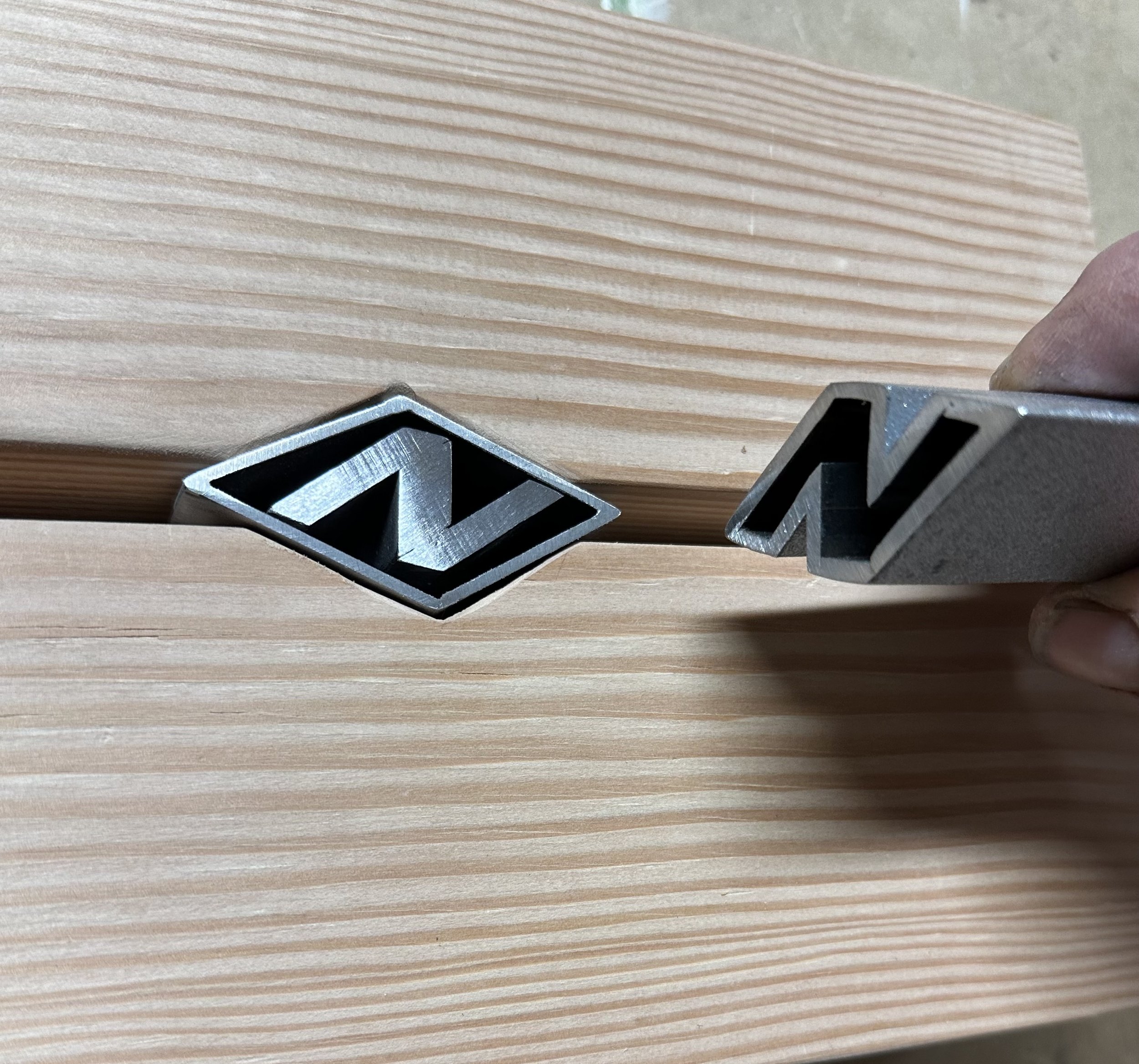 Close-up of a wooden surface with several metal pipe pieces, viewed from above.
