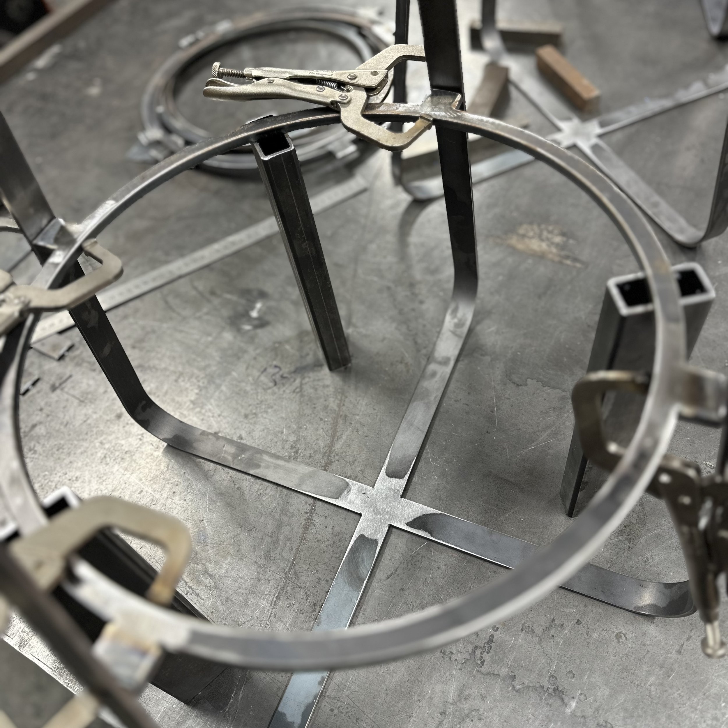 Metalwork project in progress with clamps holding curved metal pieces on a worktable.