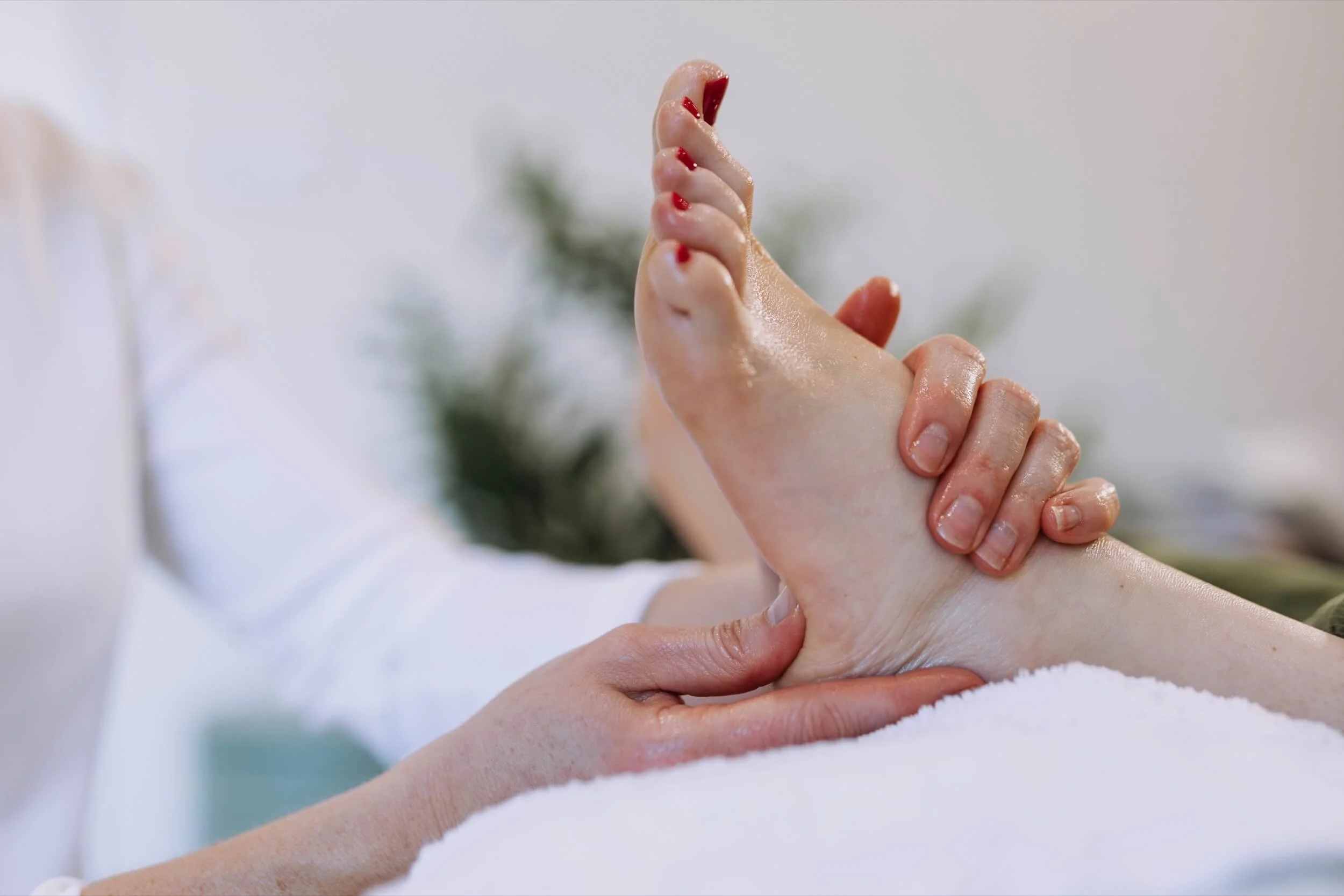 A person receiving a massage with their hand being gently massaged, in a spa or relaxation setting.