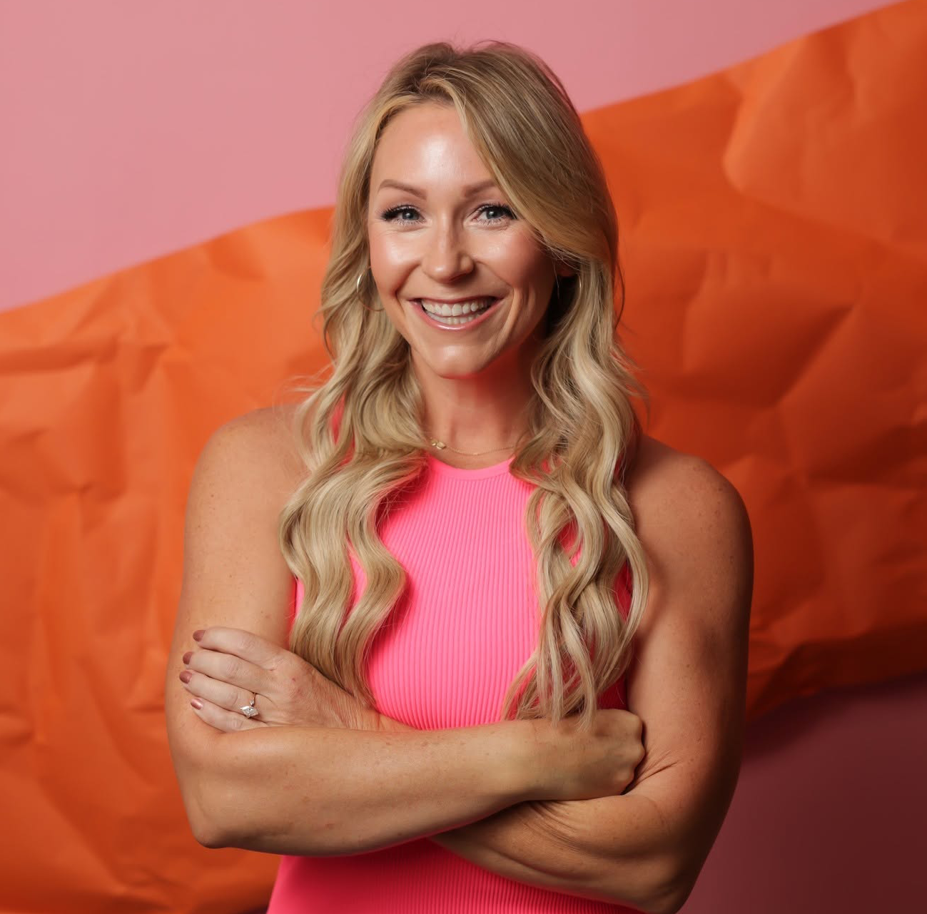 Instructor Heather Donner stands holding her arms folded, smiling. 