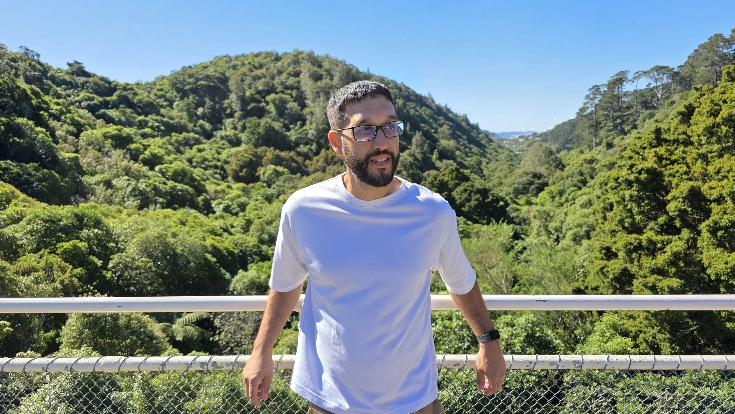 Javier Omar Meléndez-Vega, LCSW-S, an eco therapist and decolonial therapist in San Antonio, Texas, standing at the center of a dam at Zealandia in Wellington New Zealand.