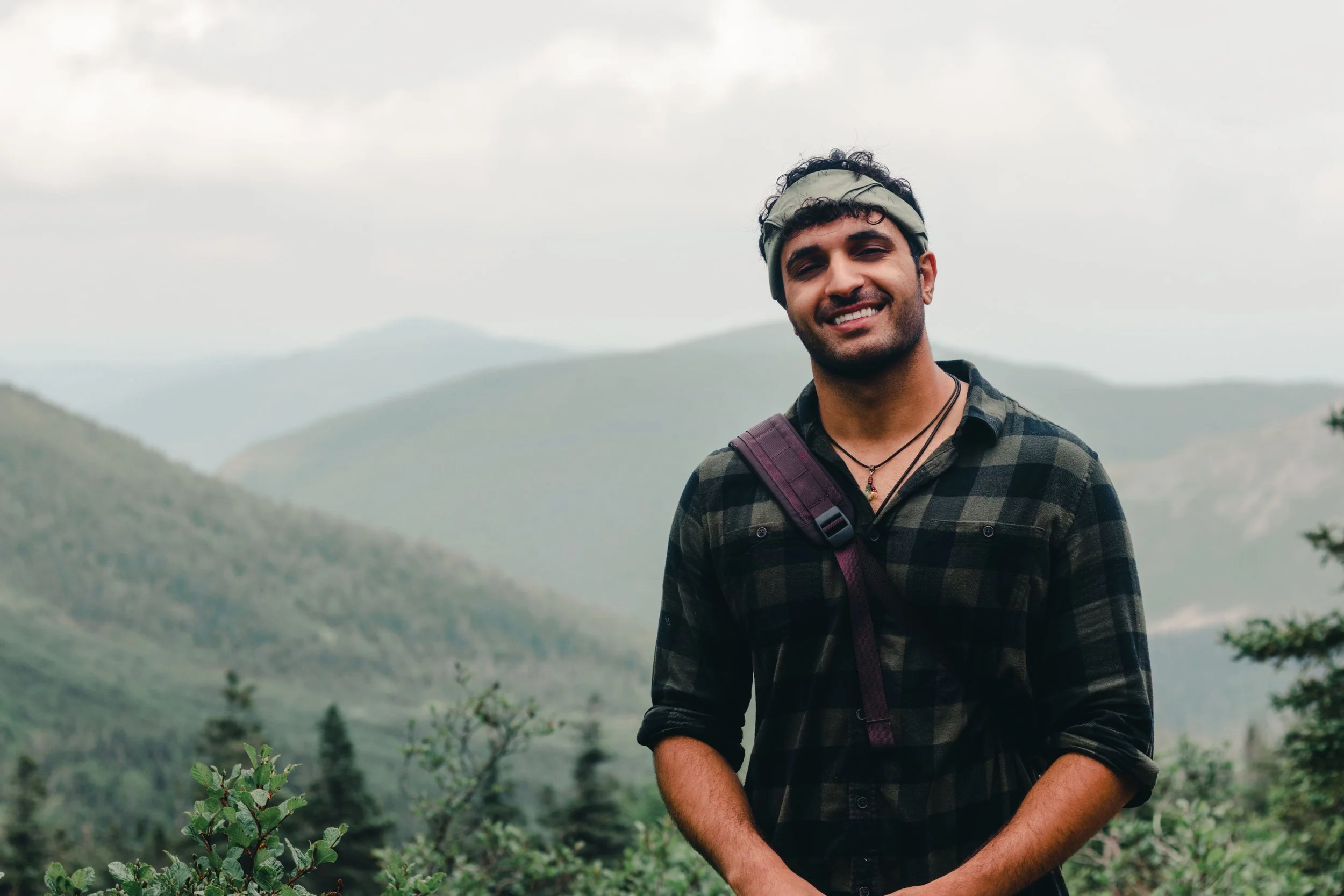 Smiling man hiking along a mountain trail in an outdoor eco-therapy environment.