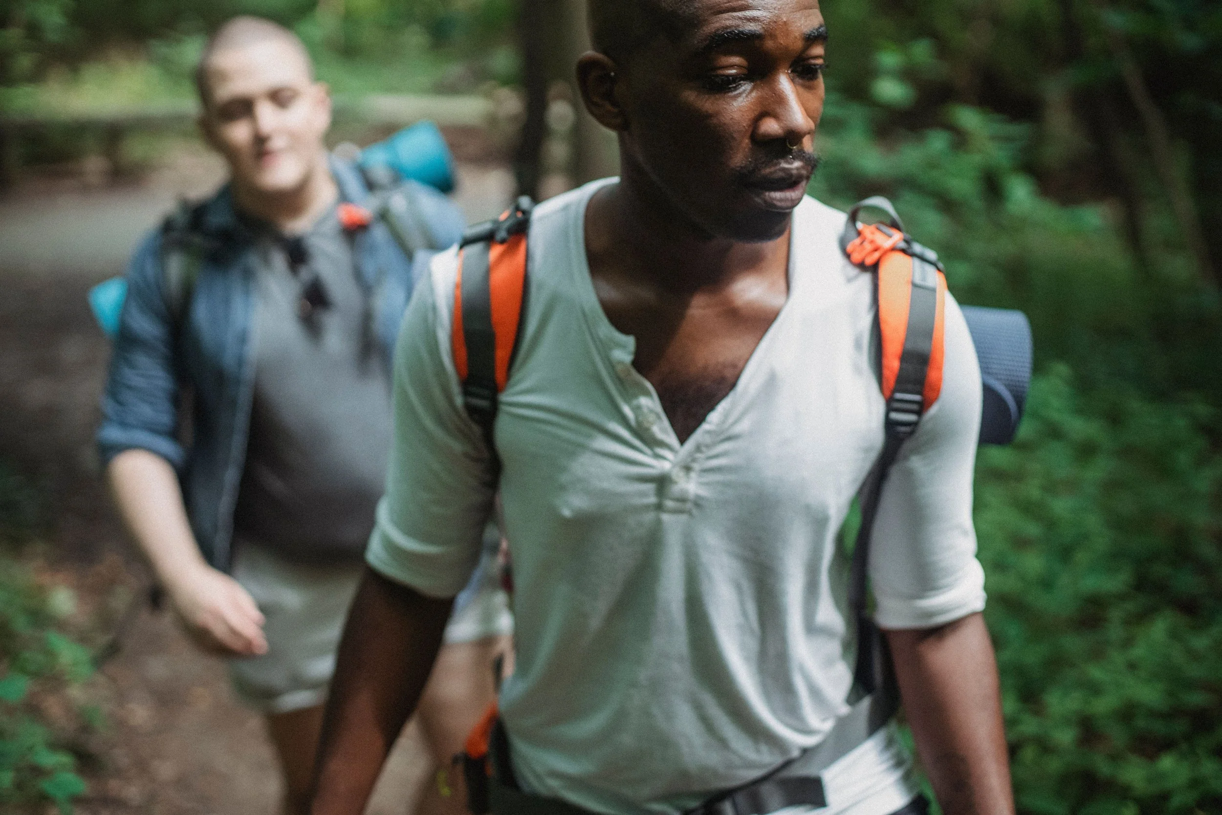 Two men walking side-by-side along a wooded trail during a walk-and-talk eco-therapy session.
