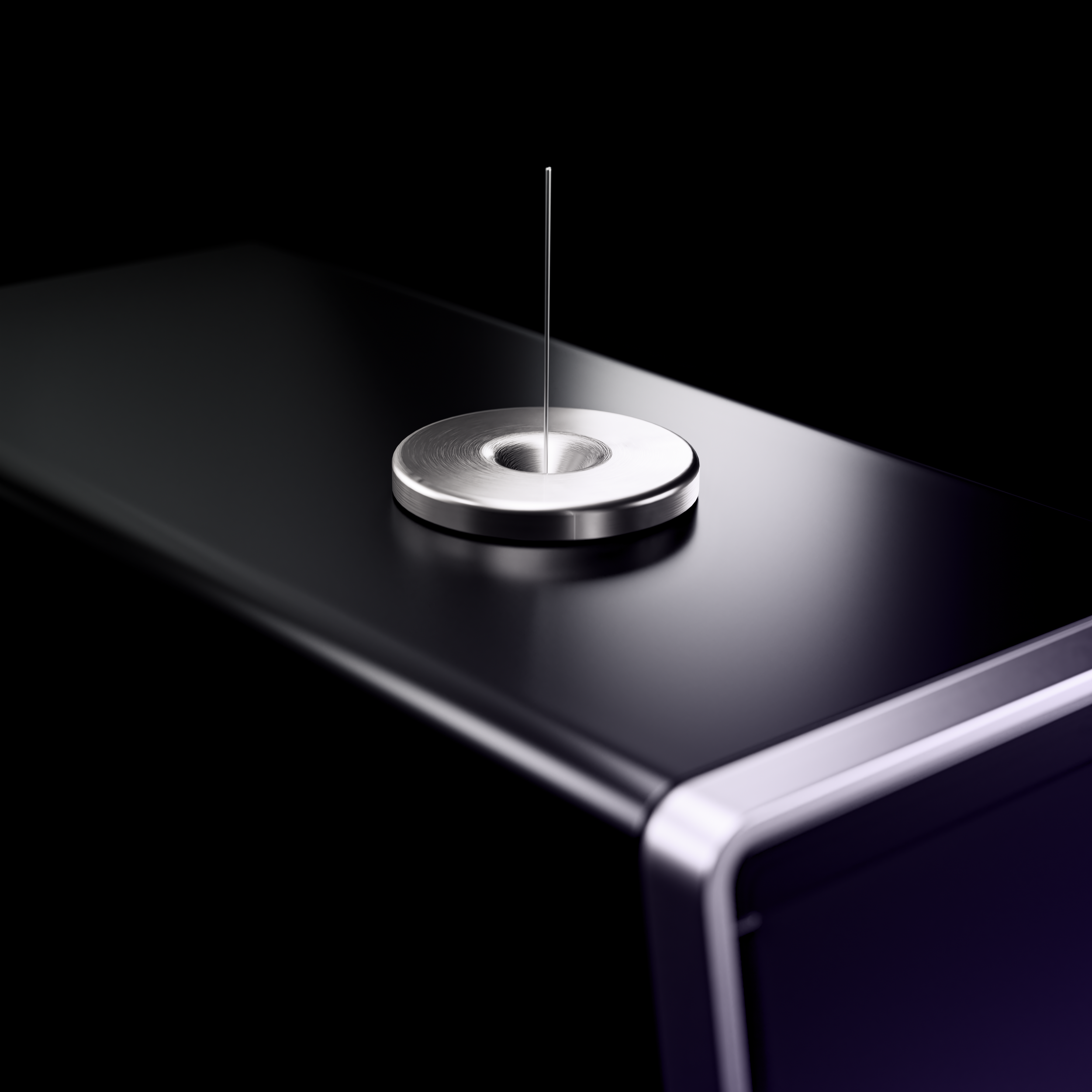 Close-up of a silver metallic object with a thin vertical rod or needle in the center, placed on a reflective surface with black background.