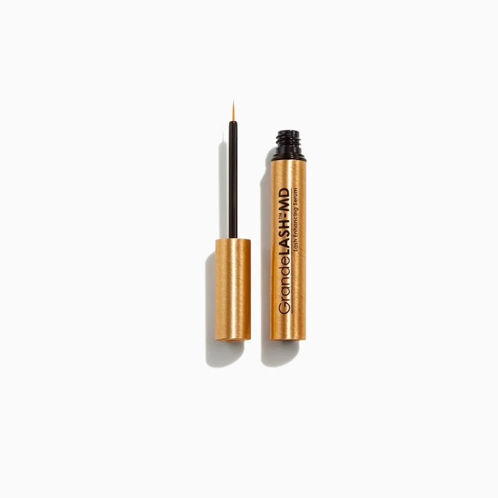 Gold-colored tube of GrandeLASH-MD lash enhancing serum with applicator brush on a white background.