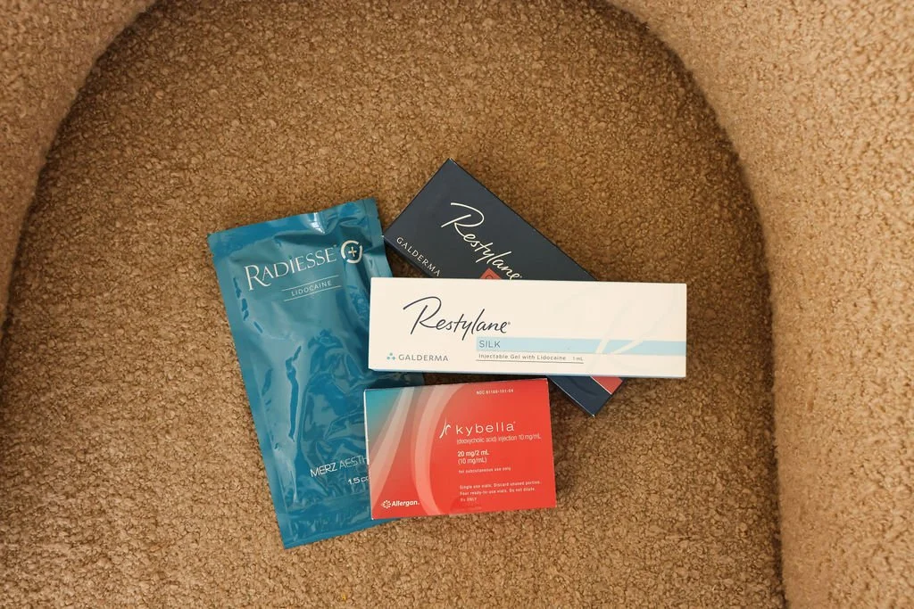 Assorted medical products including Radiesse, Restylane, and Kybella packages, placed on a beige carpet.