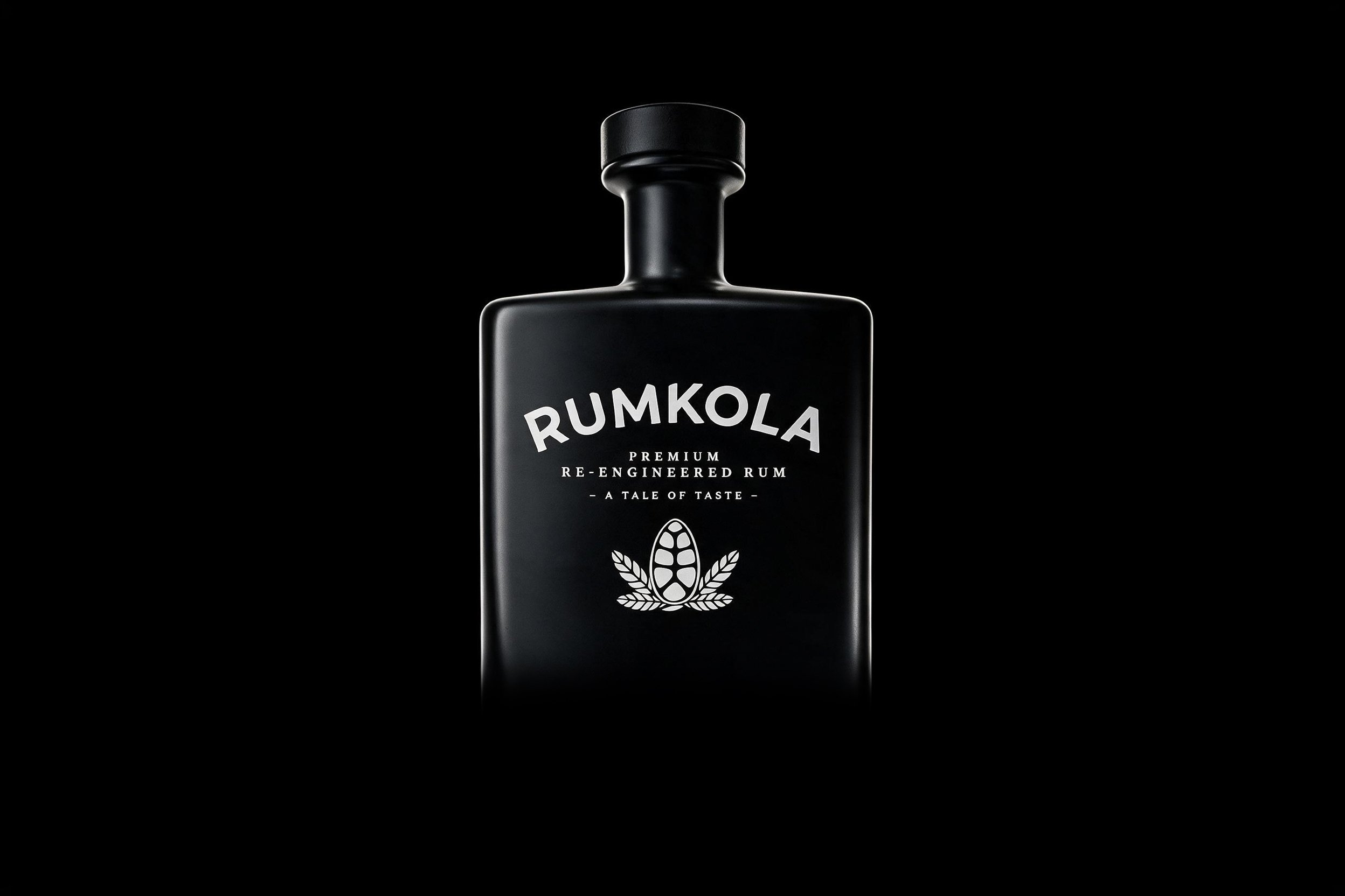 A black bottle of Rumkola premium re-engineered rum with a black background.