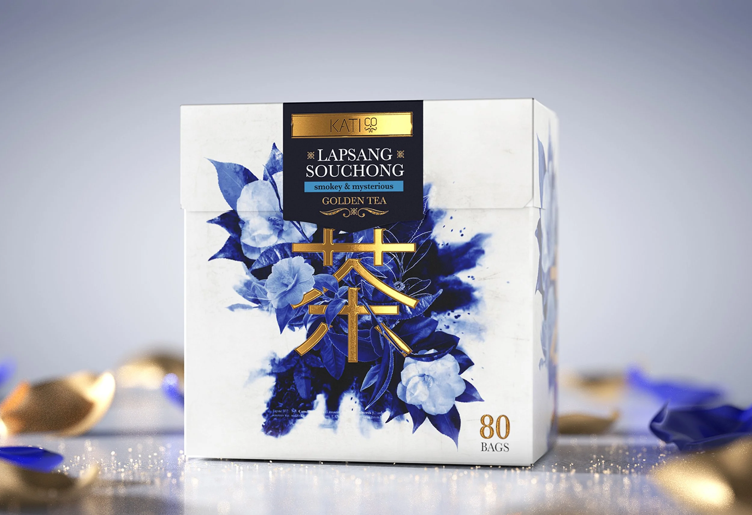 A box of Kati Co Lapsang Souchong Smoky and Mysterious Golden Tea bags with blue floral design and gold accents on the packaging.