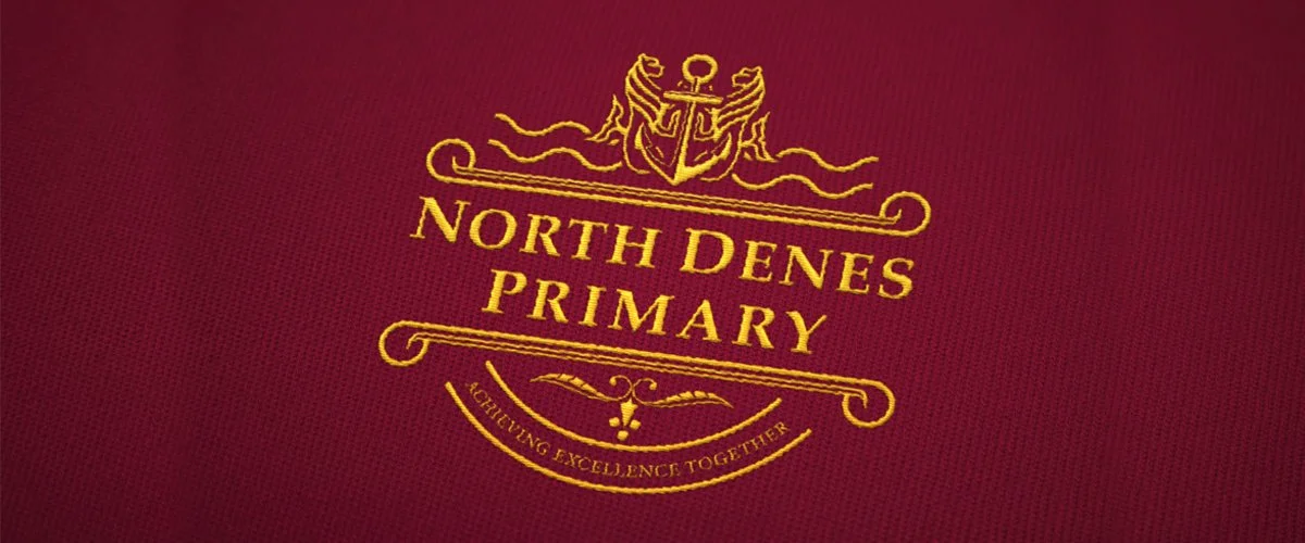 Close-up of a red fabric with a gold emblem and text that reads 'North Dunes Primary' and 'Achieving Excellence Together'.