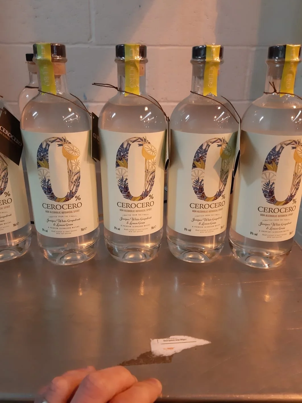Four bottles of CeroCero non-alcoholic botanical spirit with lemon grapefruit label on a metal surface.