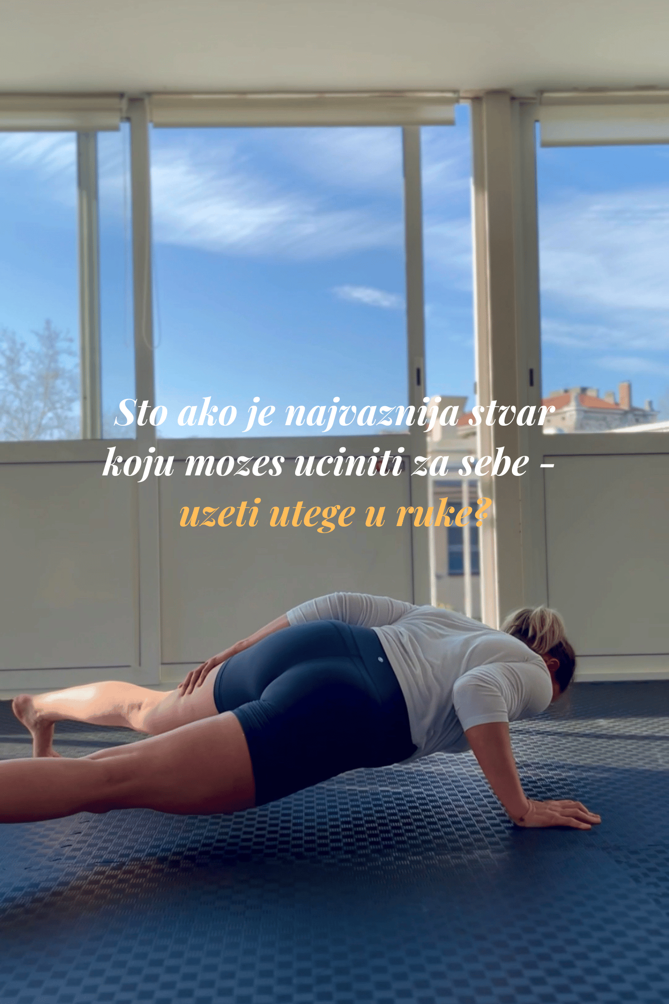 A woman practicing one arm pushup on a blue patterned mat indoors, with large windows showing a blue sky and buildings outside, and a motivational quote in Croatian overlaid on the image.