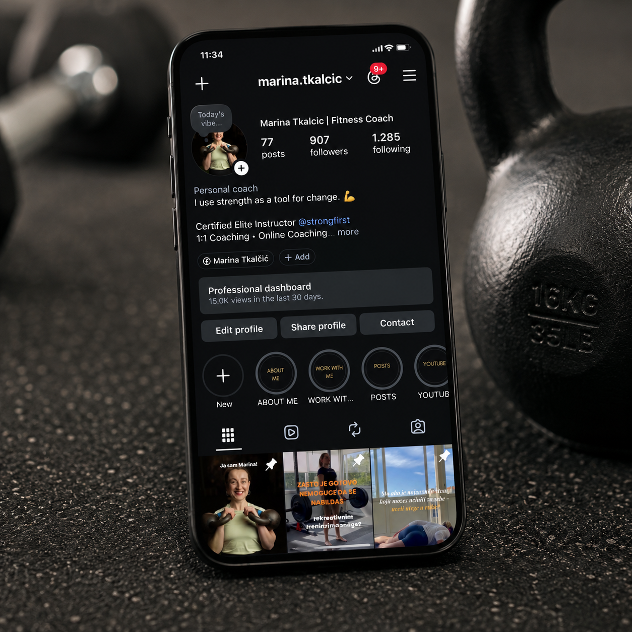 Smartphone displaying a fitness coach's social media profile on a gym floor with dumbbells in the background.