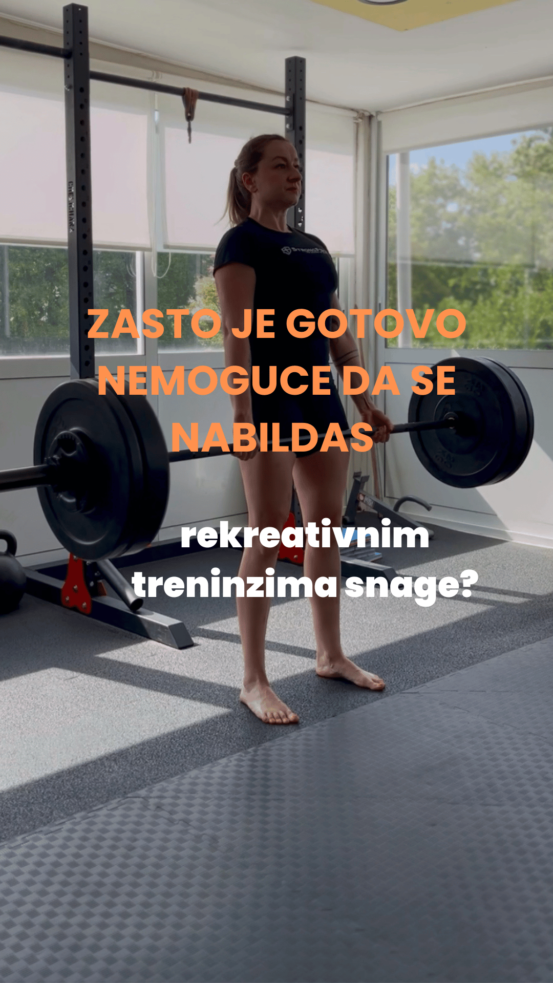 A woman in a gym standing barefoot while lifting a barbell with weights. She is indoors near large windows with a view of trees outside. Overlaid text in Serbian suggests the topic is about the benefits of strength training.