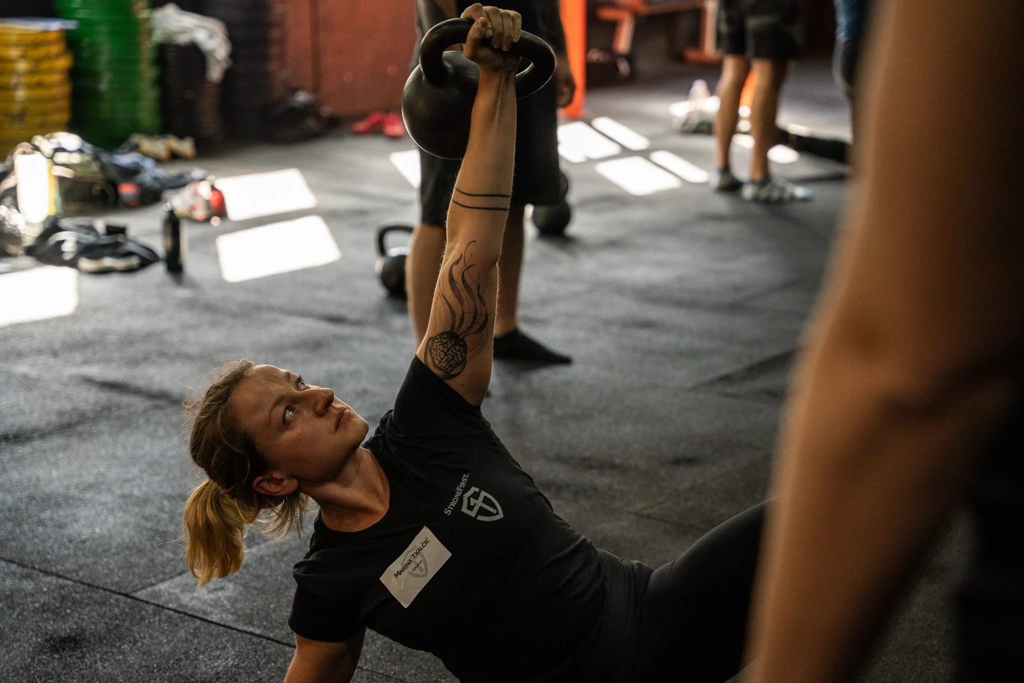 Marina Tkalcic holding a kettlebell above her chest in turkish get up pose.