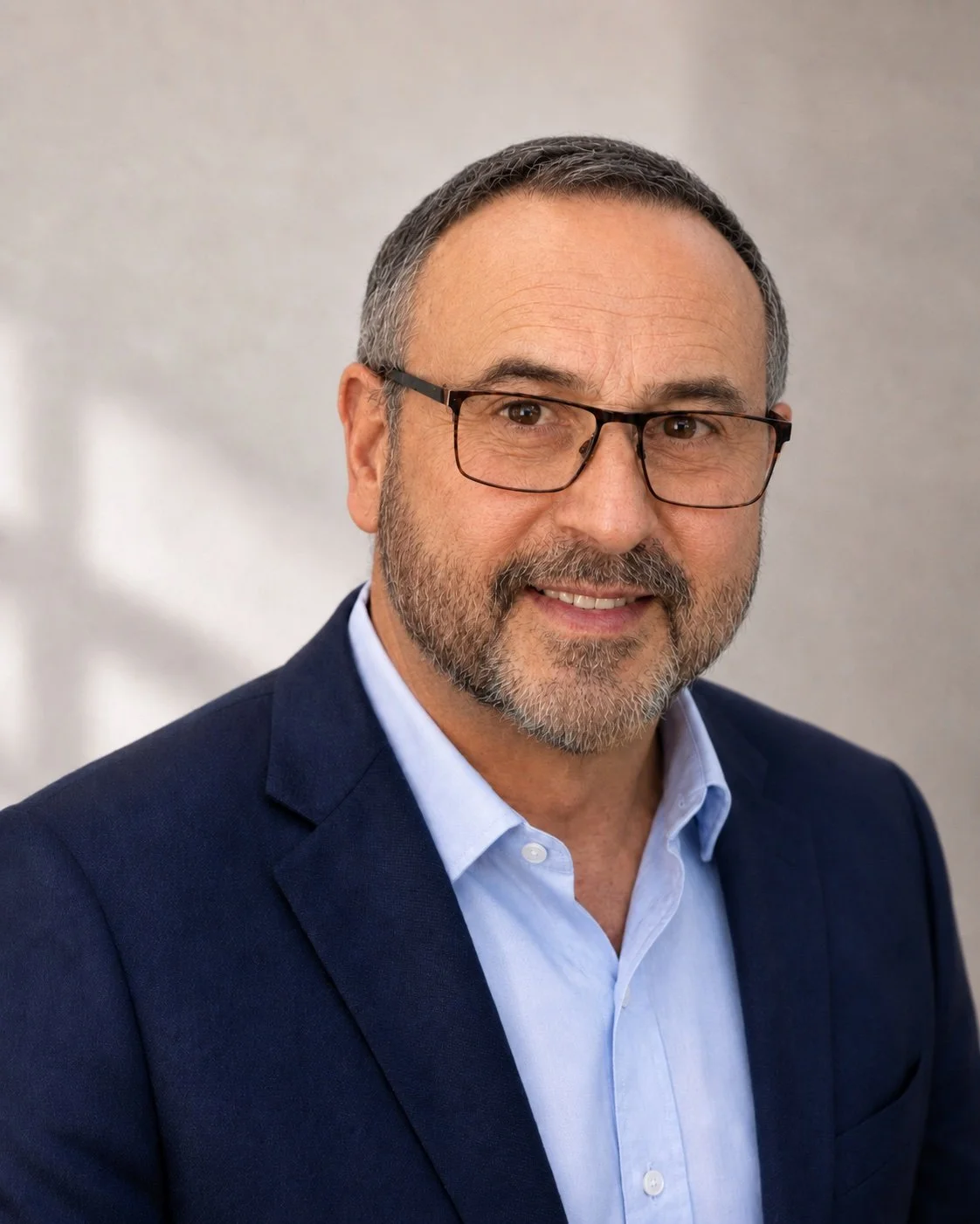 Professional headshot of Mike Shultz, author of You Can't Stop Love, smiling in a navy blazer and glasses against a neutral background.