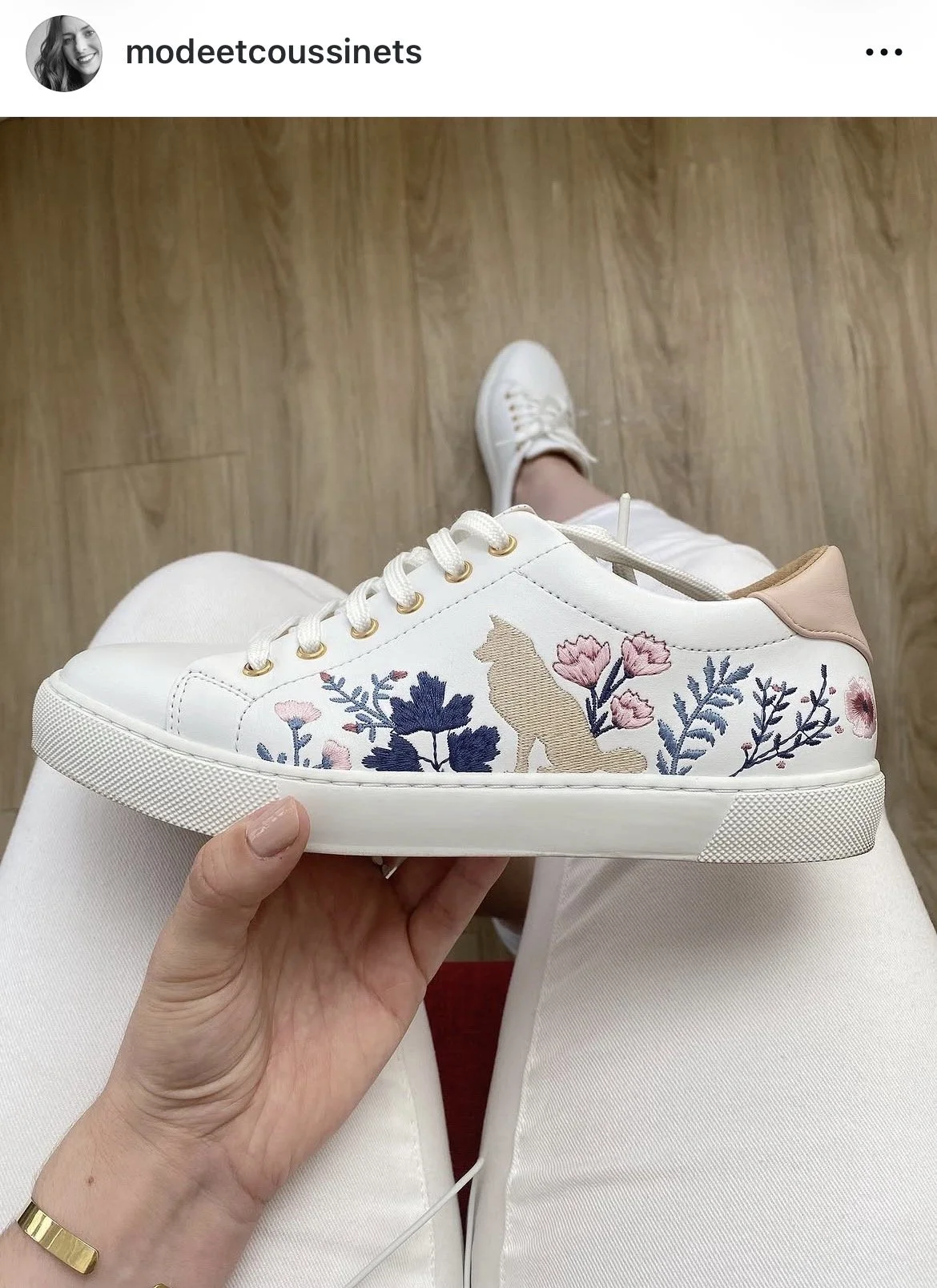 Chaussure blanche à broderie florale avec un chien et des fleurs, tenue décontractée avec pantalon blanc, chaussette blanche et chaussure blanche.