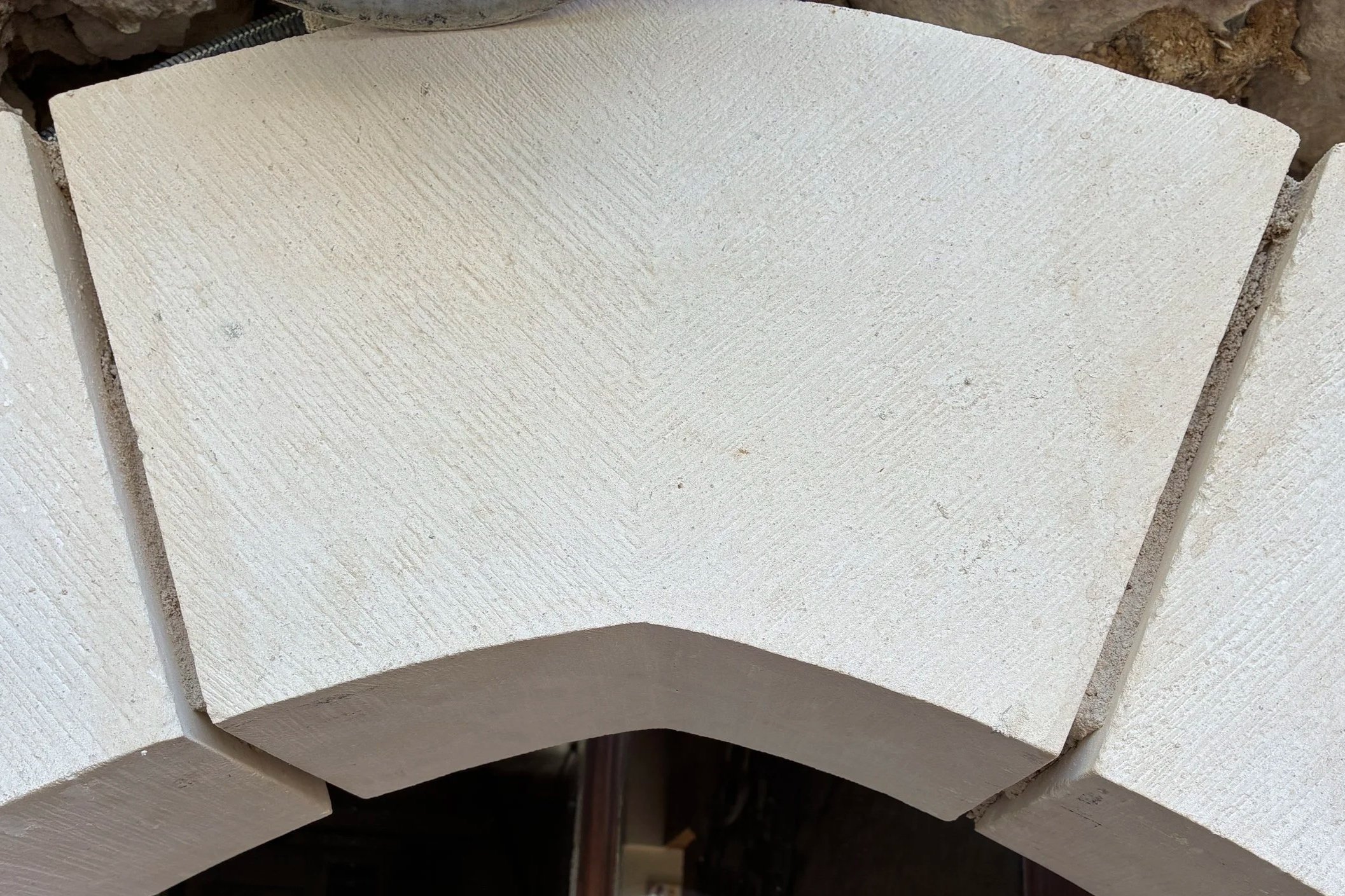 Une rangée de blocs de pierre blanche, vue en plan, avec une texture légèrement rainurée.