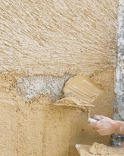 Une main appliquant un enduit sur un mur en utilisant une spatule.