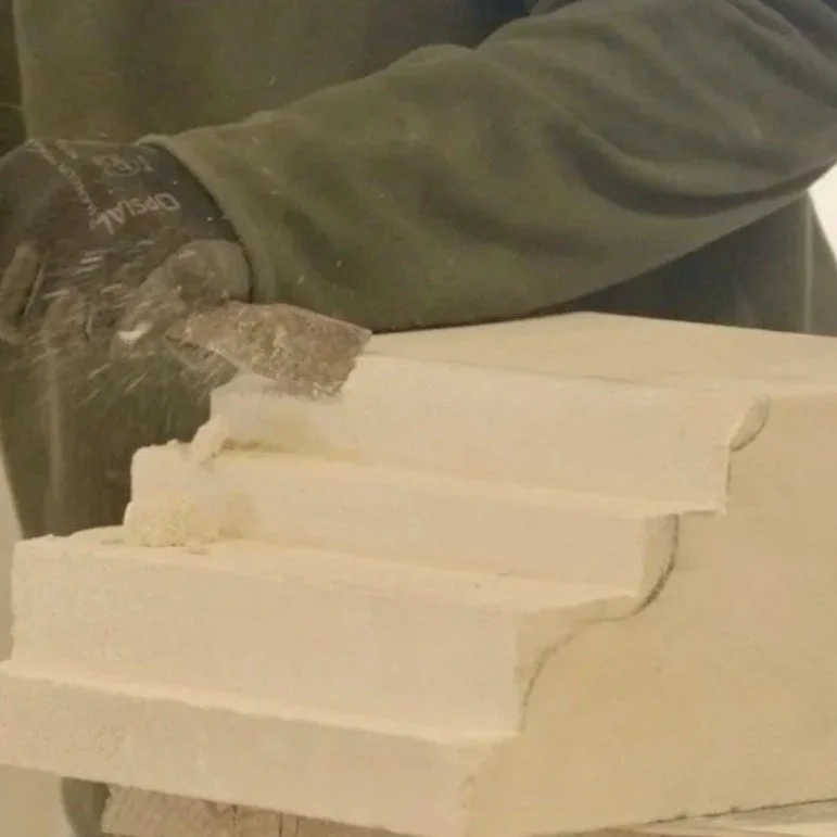 Un technicien en formation utilisant une scie pour couper du plâtre ou de la pierre suffise à une sculpture.