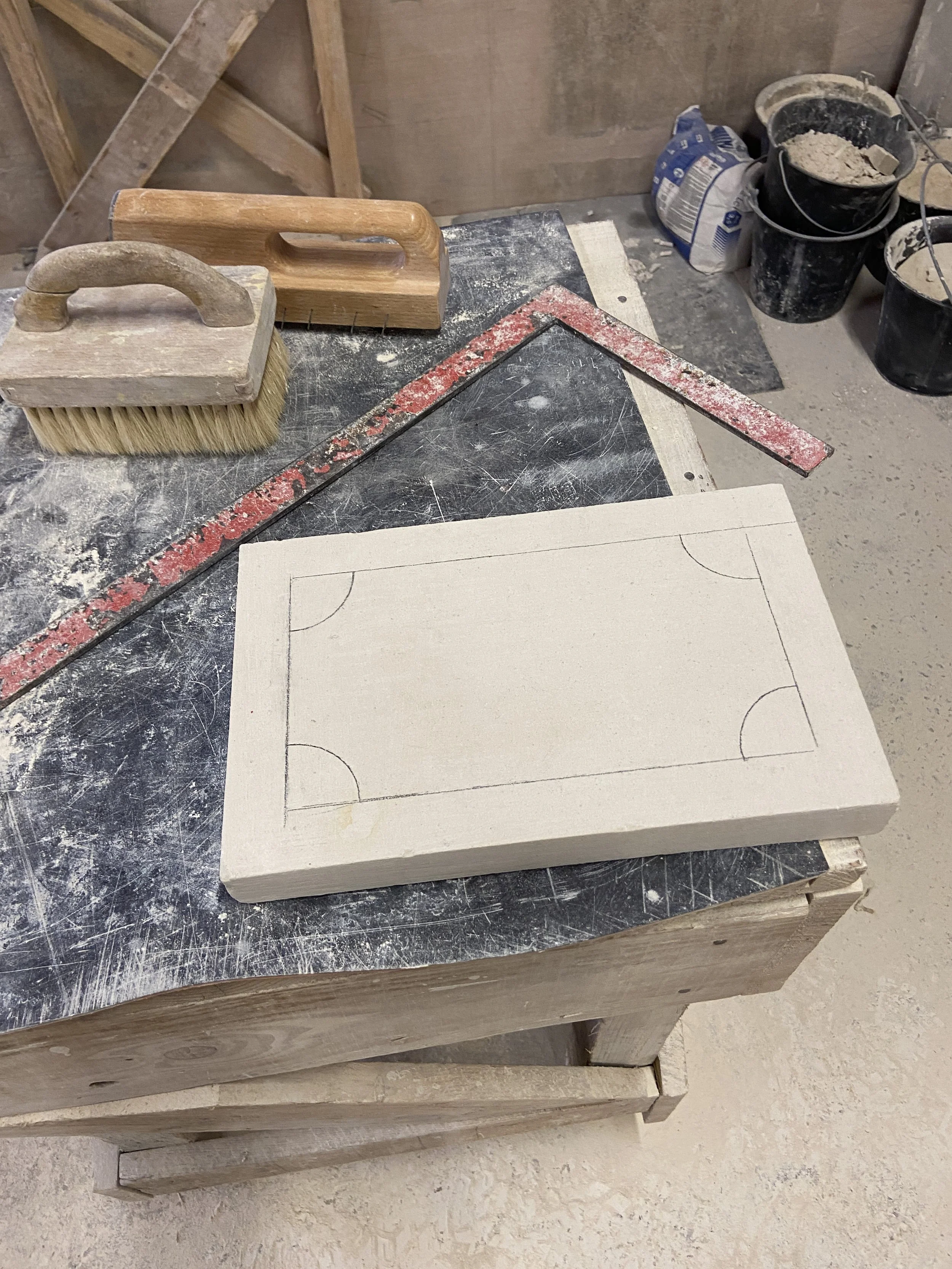 Planche à dessin avec dessin d'un terrain de basketball tracé au crayon sur une table de travail en bois dans un atelier de bricolage.