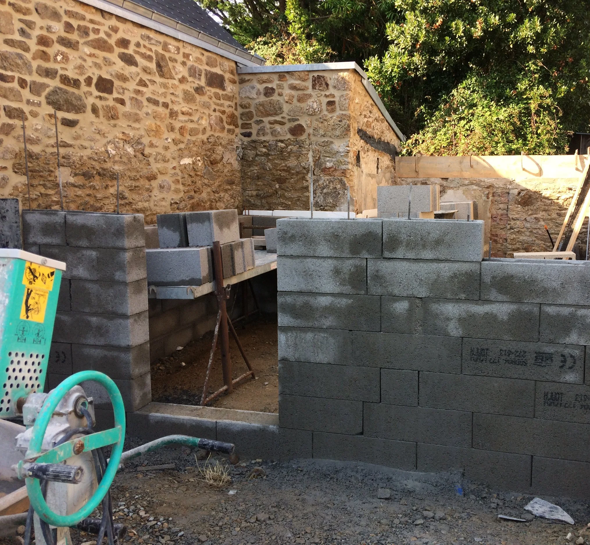 Construction d'un mur en pierres avec des blocs en béton empilés dans un espace extérieur.