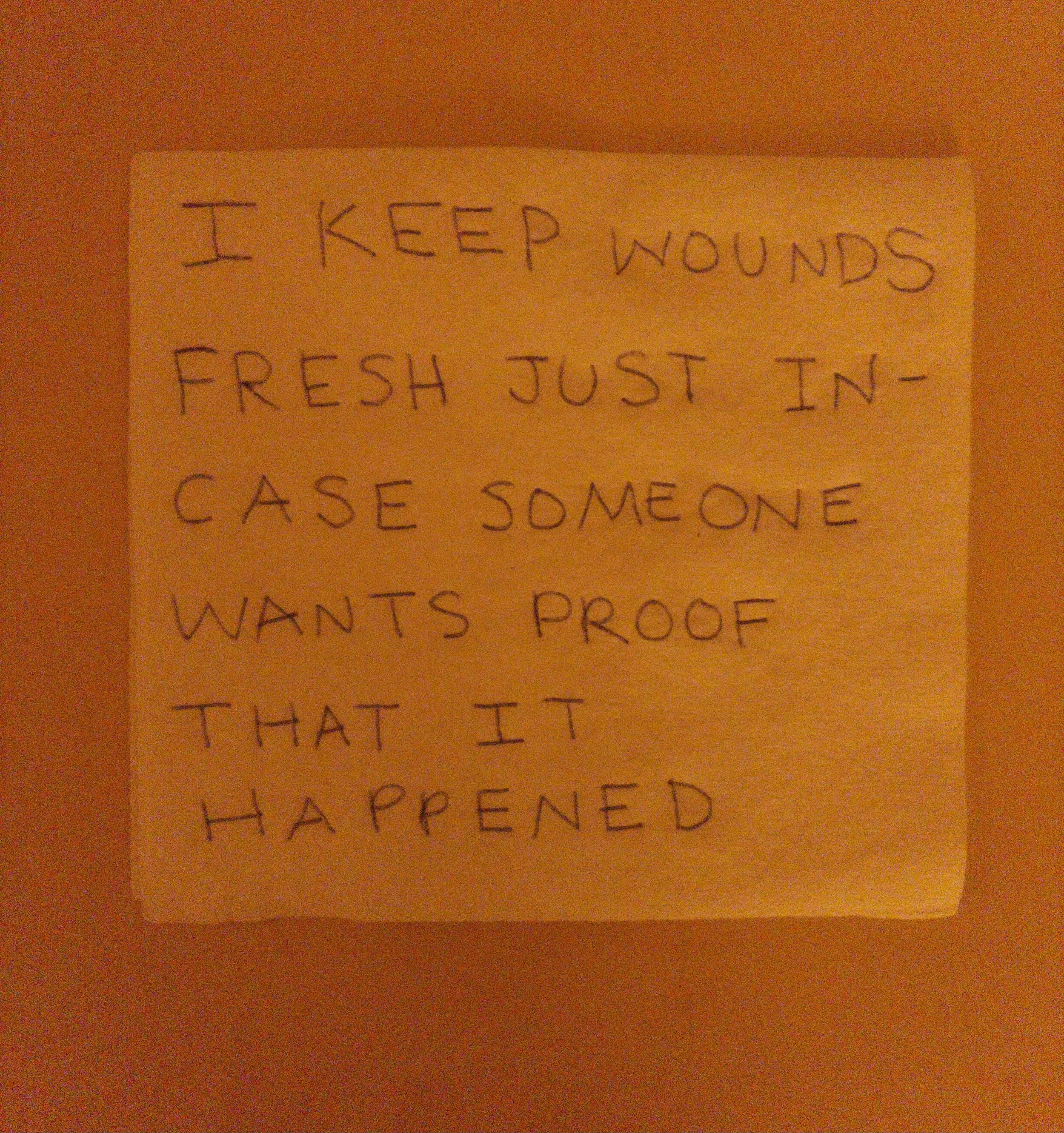 A handwritten note on paper reads, "I KEEP WOUNDS FRESH JUST IN- CASE SOMEONE WANTS PROOF THAT IT HAPPENED".
