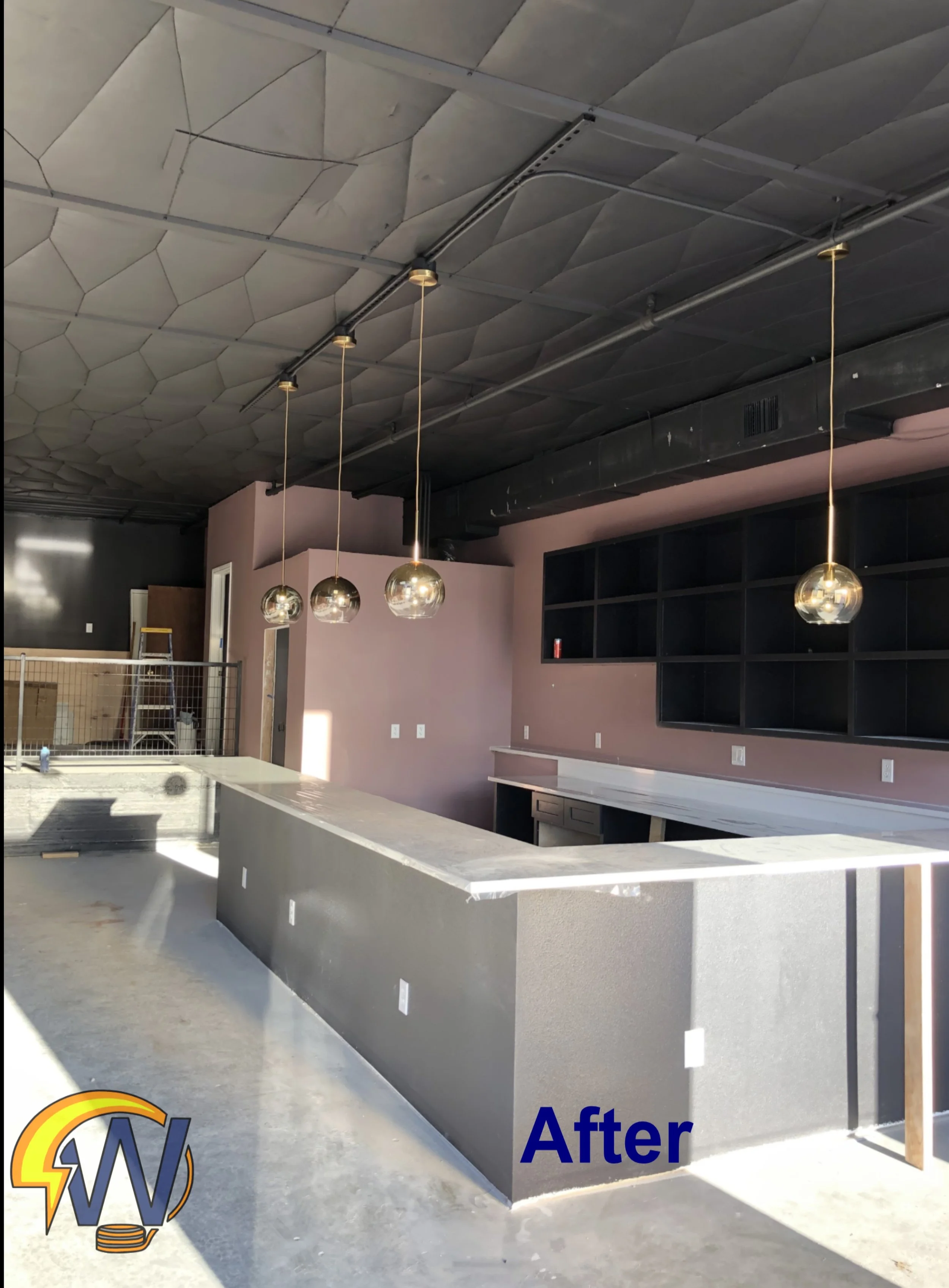 Photo showing a renovated indoor space with a polished concrete floor, a large light-colored kitchen island, black shelving units, pendant lights hanging from the ceiling, and a ceiling with geometric patterns. The word 'After' indicates the completi