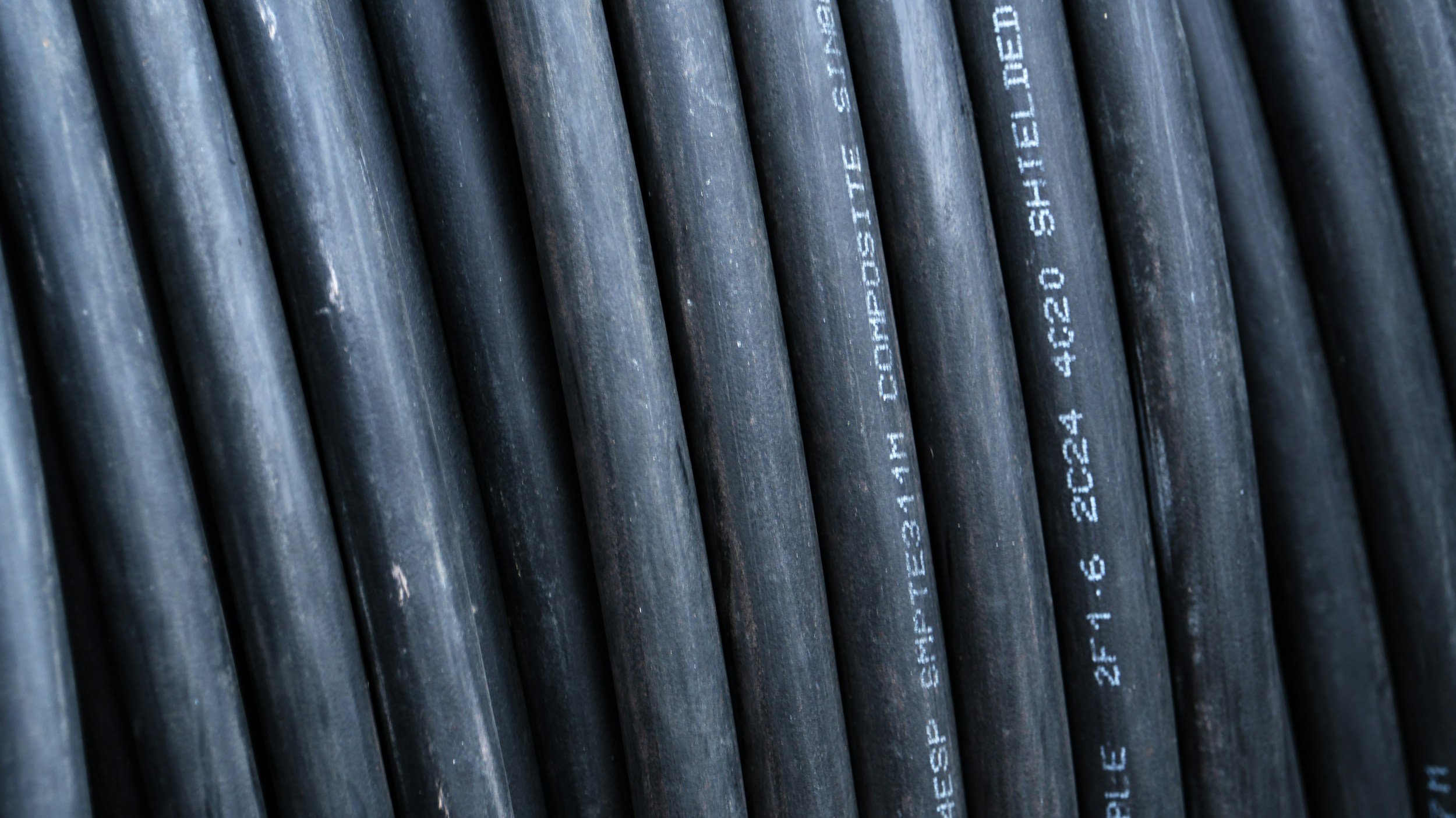 Close-up of black electrical cables with white printed specifications and markings.