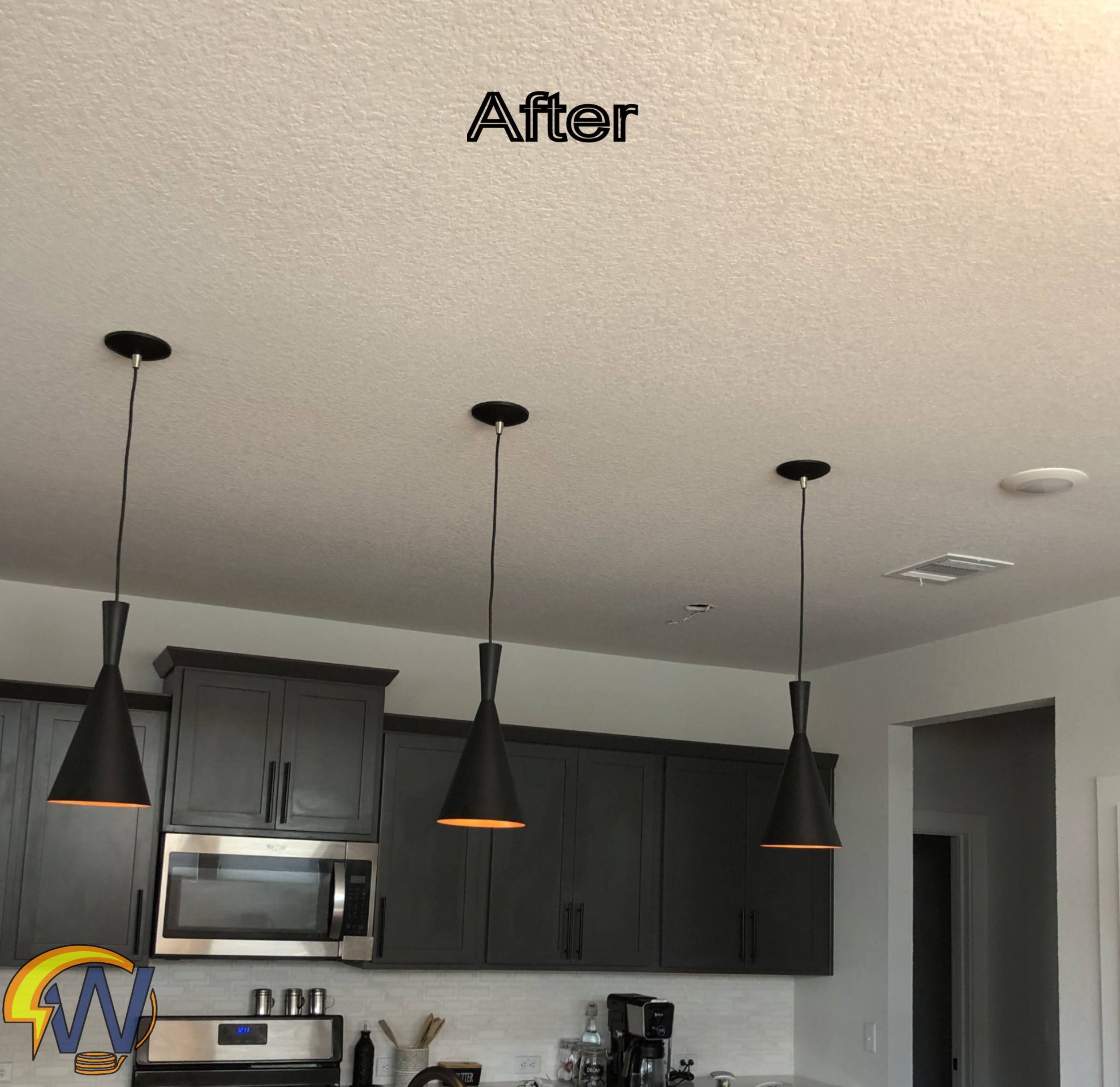 Kitchen with gray cabinets, black pendant lights, microwave oven, small appliances, and utensils on the countertop. Ceiling with textured white finish.