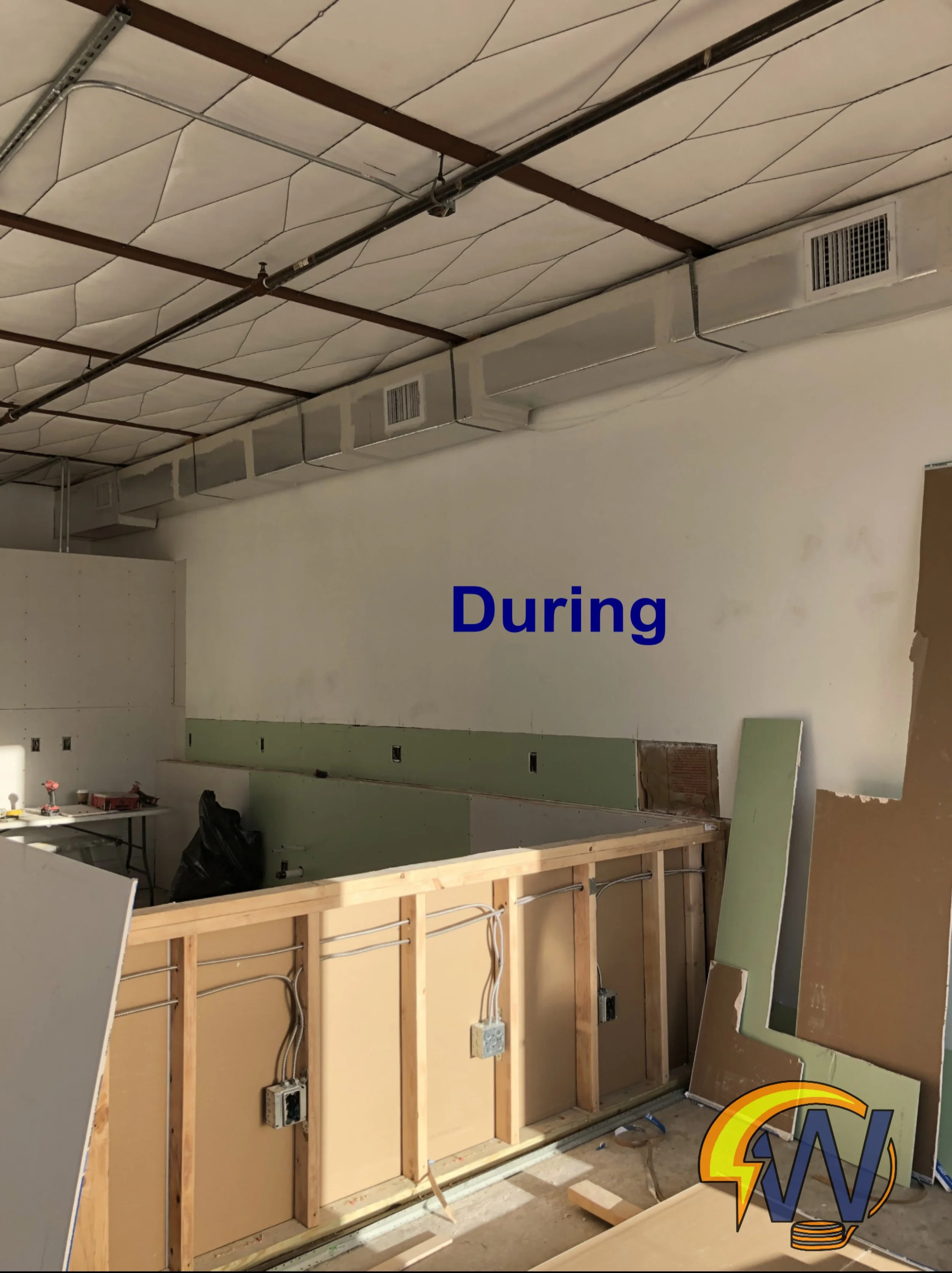 Construction site showing wall framing, electrical outlets, and HVAC ducts in a room with a partially finished ceiling.