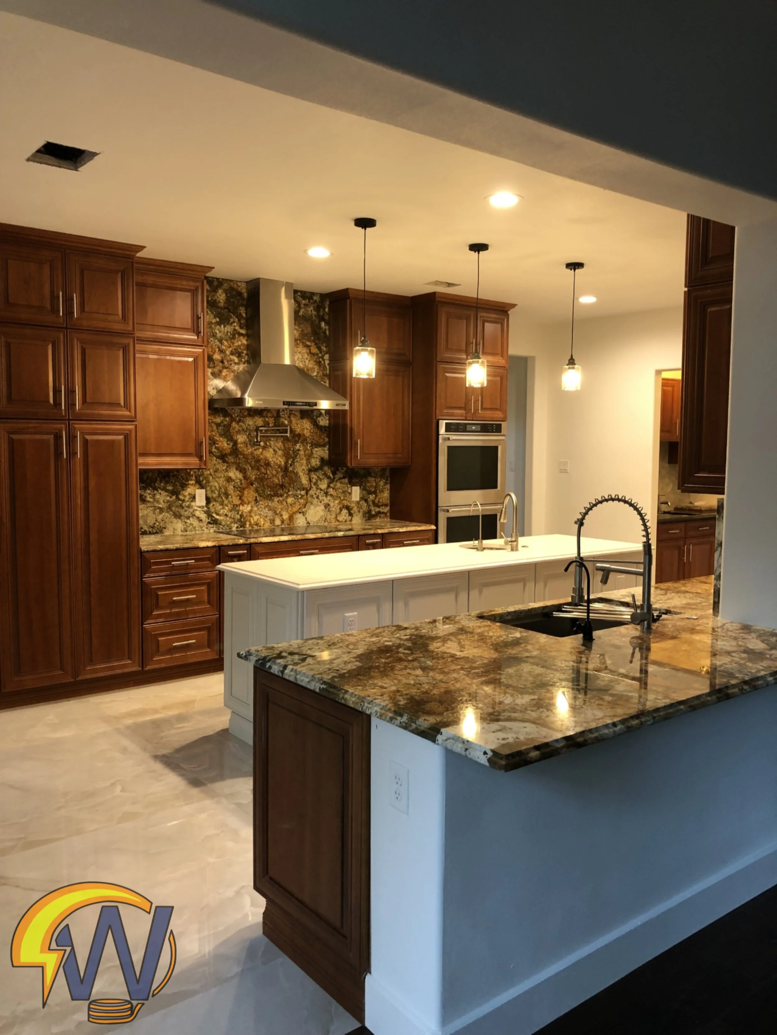 Kitchen with brown wooden cabinets, granite countertops, stainless steel range hood, built-in oven, and pendant lighting over the island.