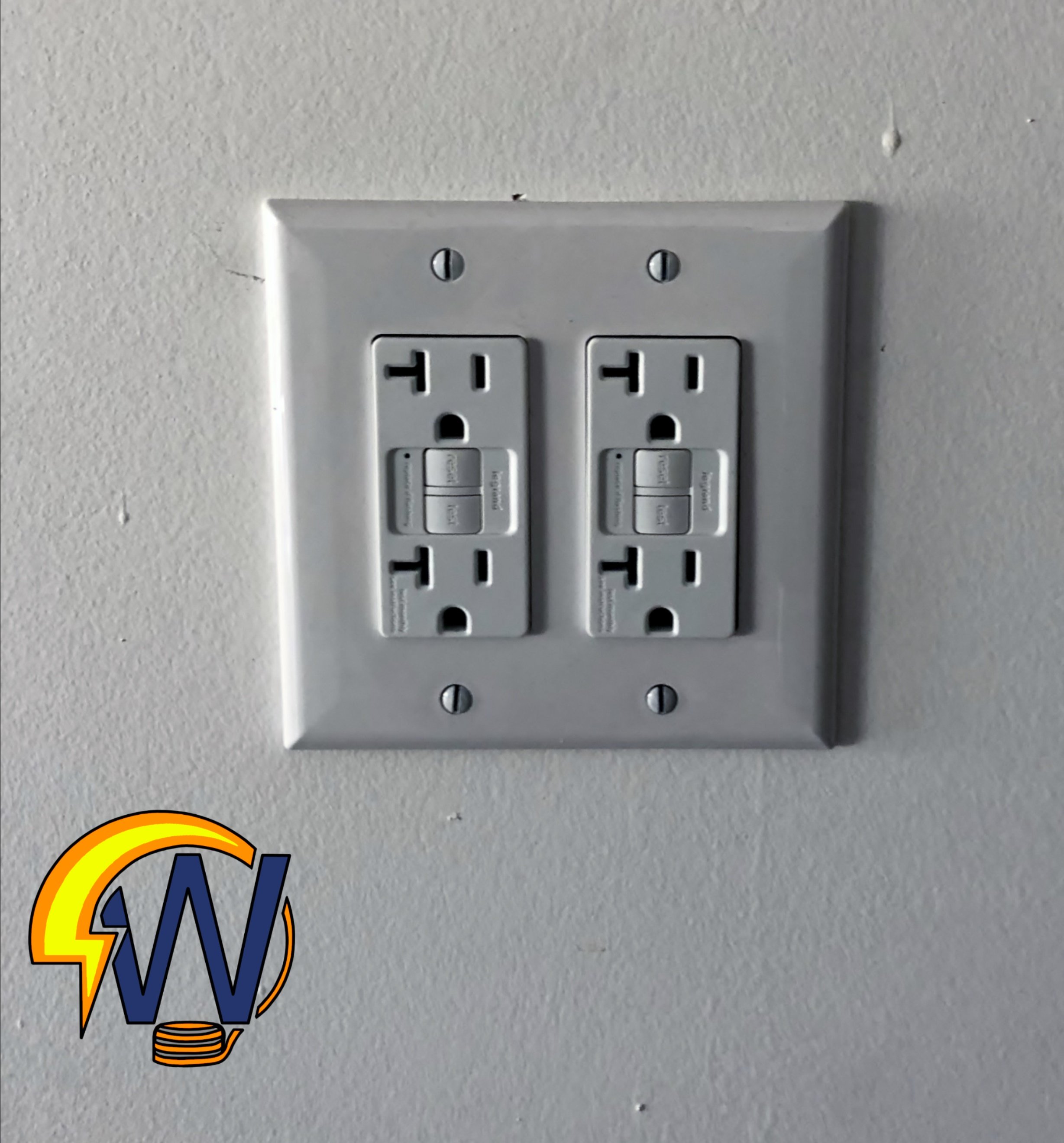 A close-up of a standard white electrical wall outlet with two sockets and a metal cover plate secured by two screws.