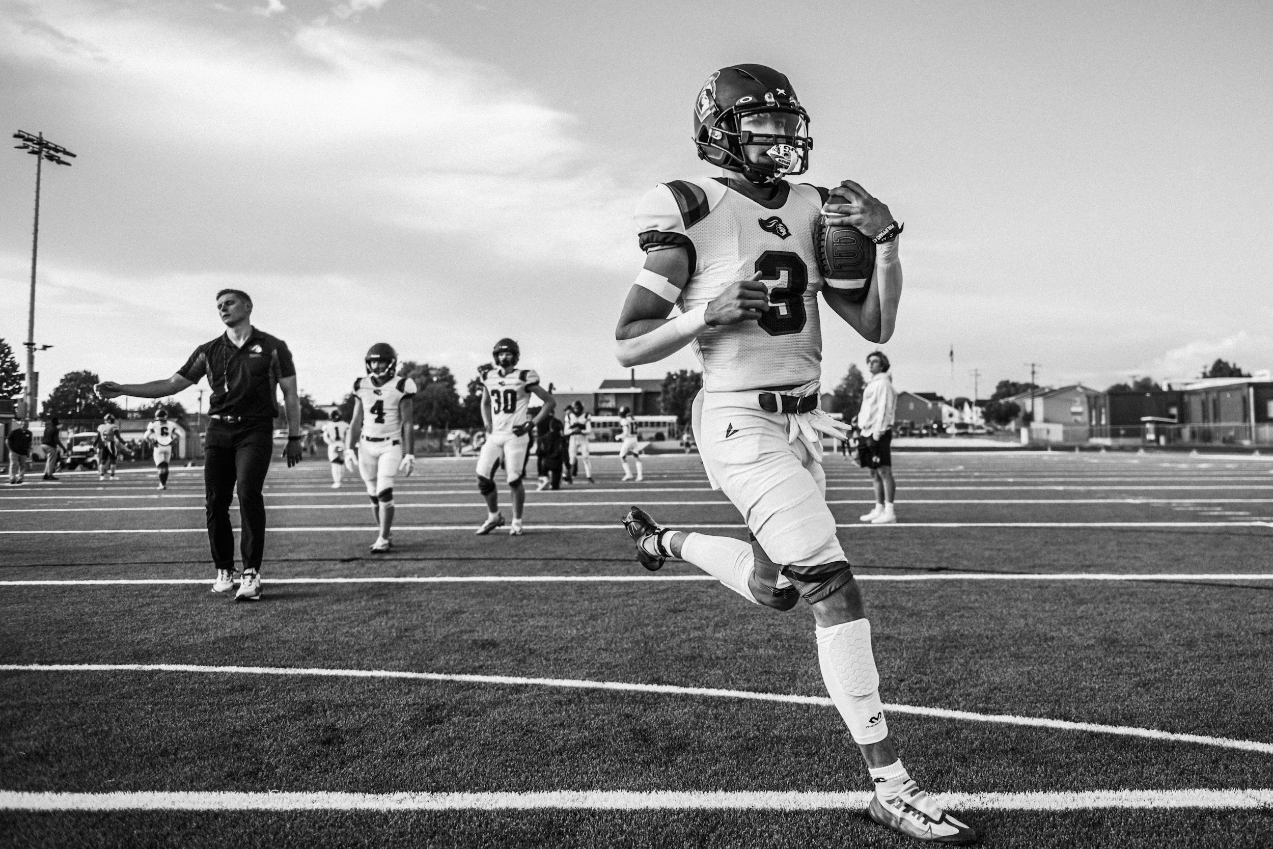 young athlete carrying football across field
