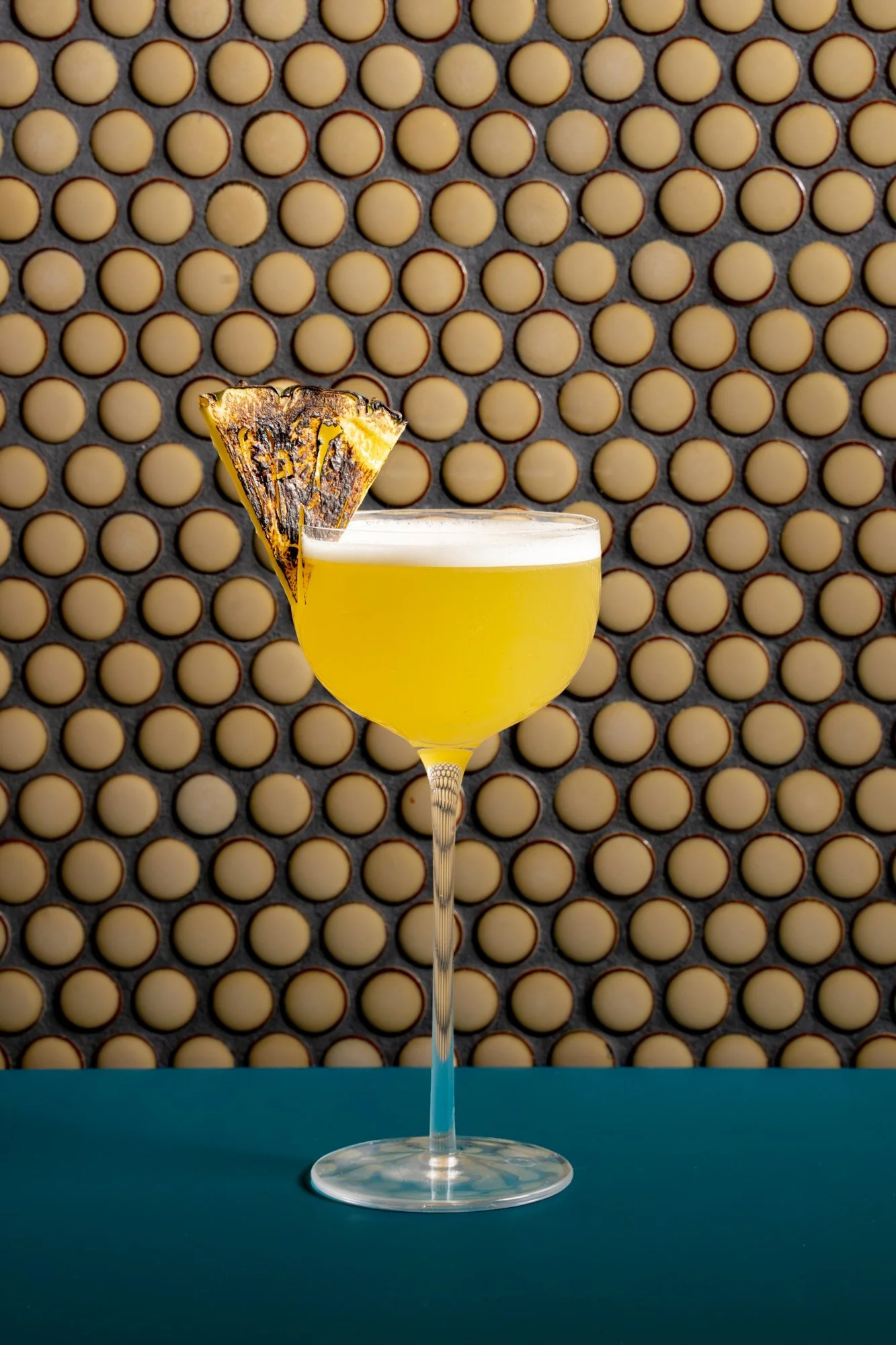 Yellow pineapple cocktail in a coupe glass with a pineapple garnish