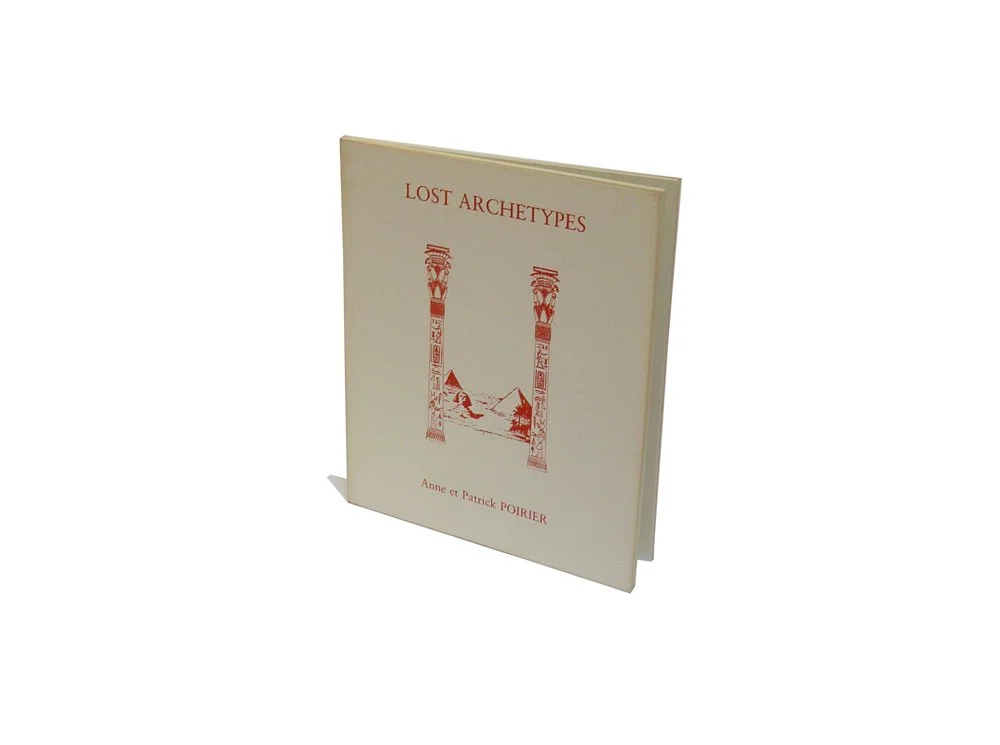 A book titled "Lost Archetypes" by Anne and Patrick Poirier, featuring a cover with a red illustration of two Egyptian-style columns and pyramids.