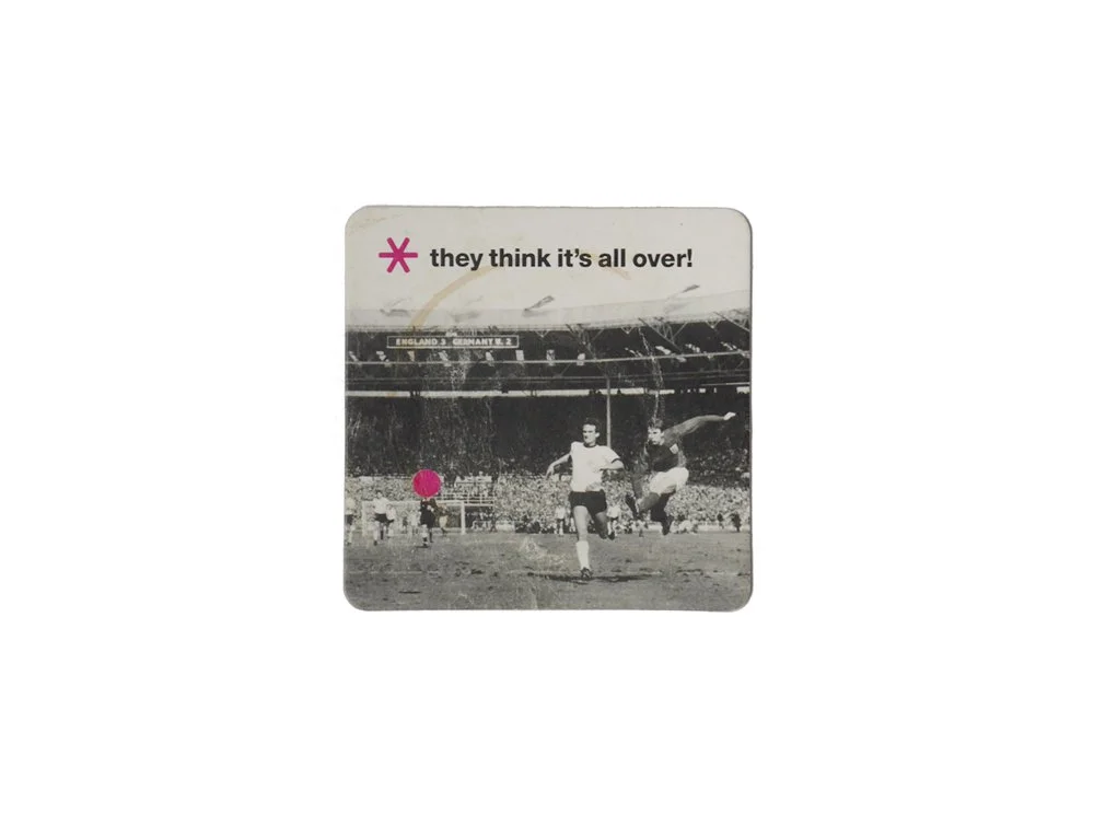 Black and white photograph of a soccer match in a stadium with players running, a pink dot in the foreground, and the phrase "they think it’s all over!" at the top.